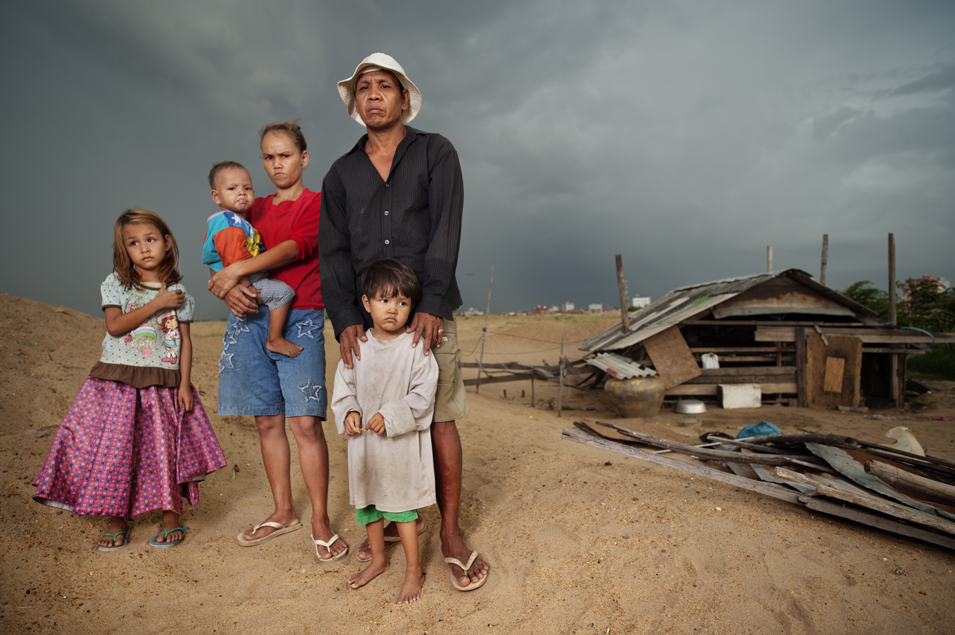  A family stands in front of their house, which is the only house left from an entire community. The family opposes the government's demands for forced relocation ( land grabbing ), Boeung Kak lake, Phnom Penh / Cambodia 