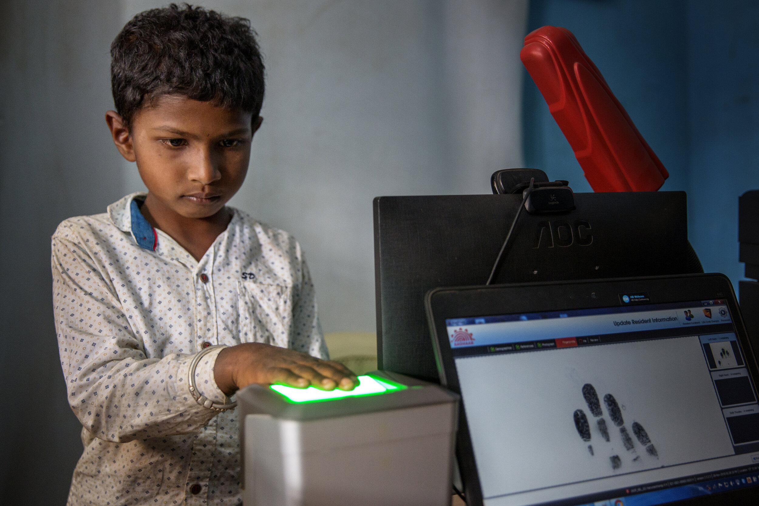  A young boy is scanning his fingerprints in order to store his biometric data into the governmental program Aadhaar, Bangalore/ India -2018 