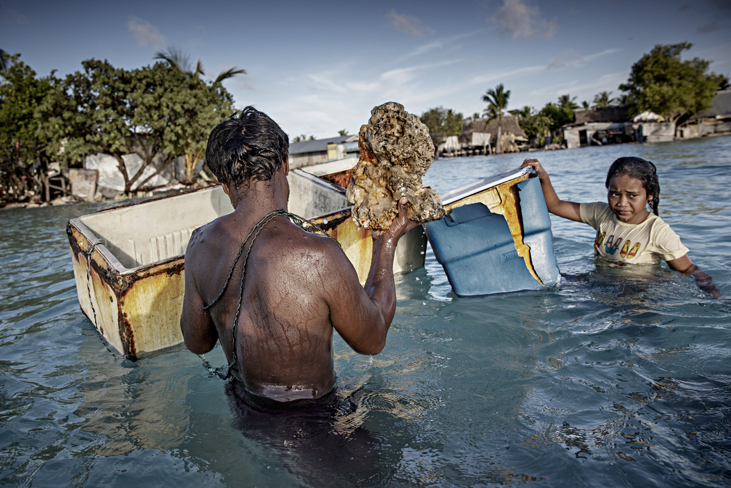  Family members gather rocks and corals from the seabed to build a wall as protection against rising sea levels / Kiribati- 2015 