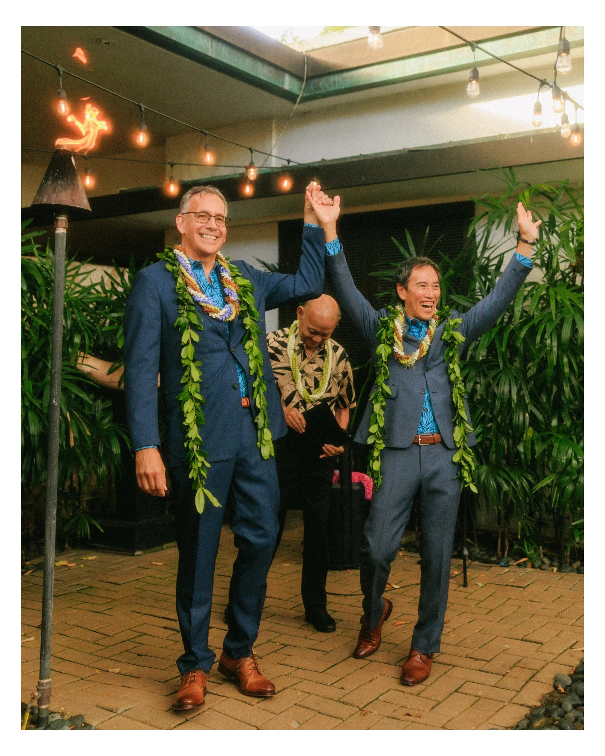 Newly married couple celebrating after their ceremony at The Pacific Club in Honolulu, Hawaii. Joyful wedding portraits featuring Hawaiian leis and tropical surroundings.