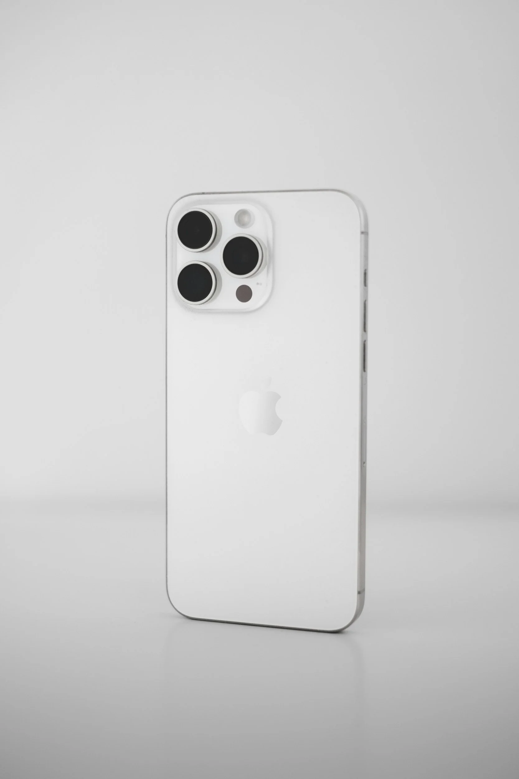 Two iPhones, one black and one white, placed on a blue surface next to a pink floral box and some papers.