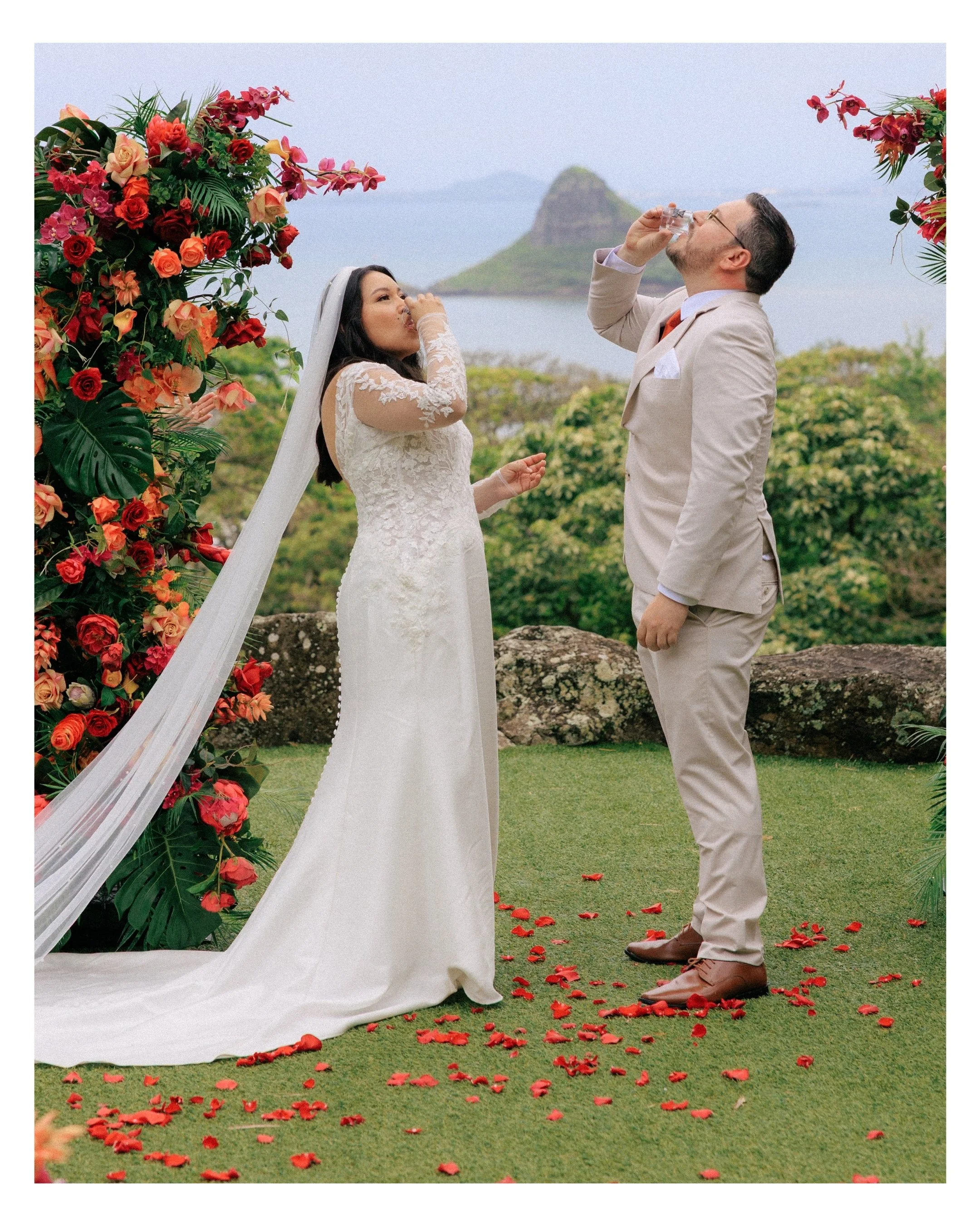 Bride and groom during ceremony at Kualoa Ranch with Chinaman’s Hat island in background and guests celebrating Hawaii elopement.