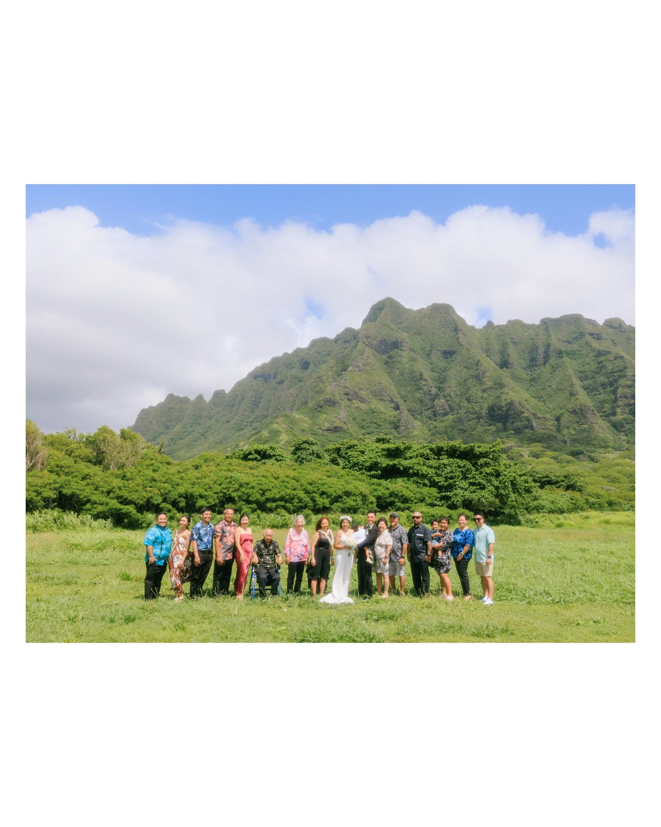 Small intimate wedding group photo at Kualoa Regional Park featuring family and guests surrounded by the Koʻolau Mountains on Oahu’s east side.