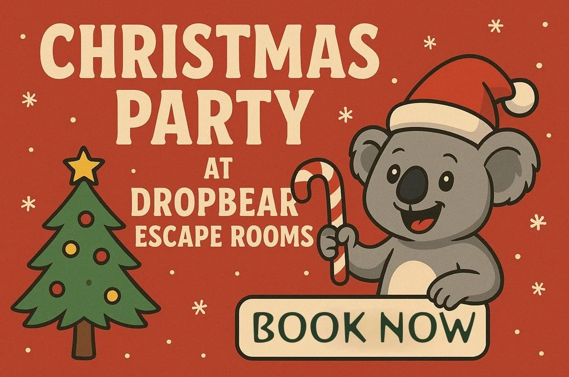 Picture of a koala wearing a santa hat at christmas with a christmas tree, advertising christmas parties at dropbear escape rooms.  The words "book now" are in a box held by the koala.