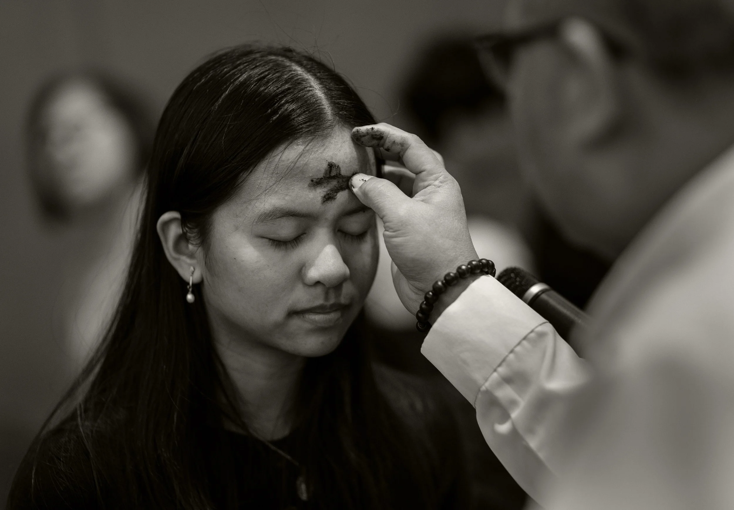 a Catholic faithful has a cross marked on her forehead with ash during Ash Wednesday, first day of the Lent season
