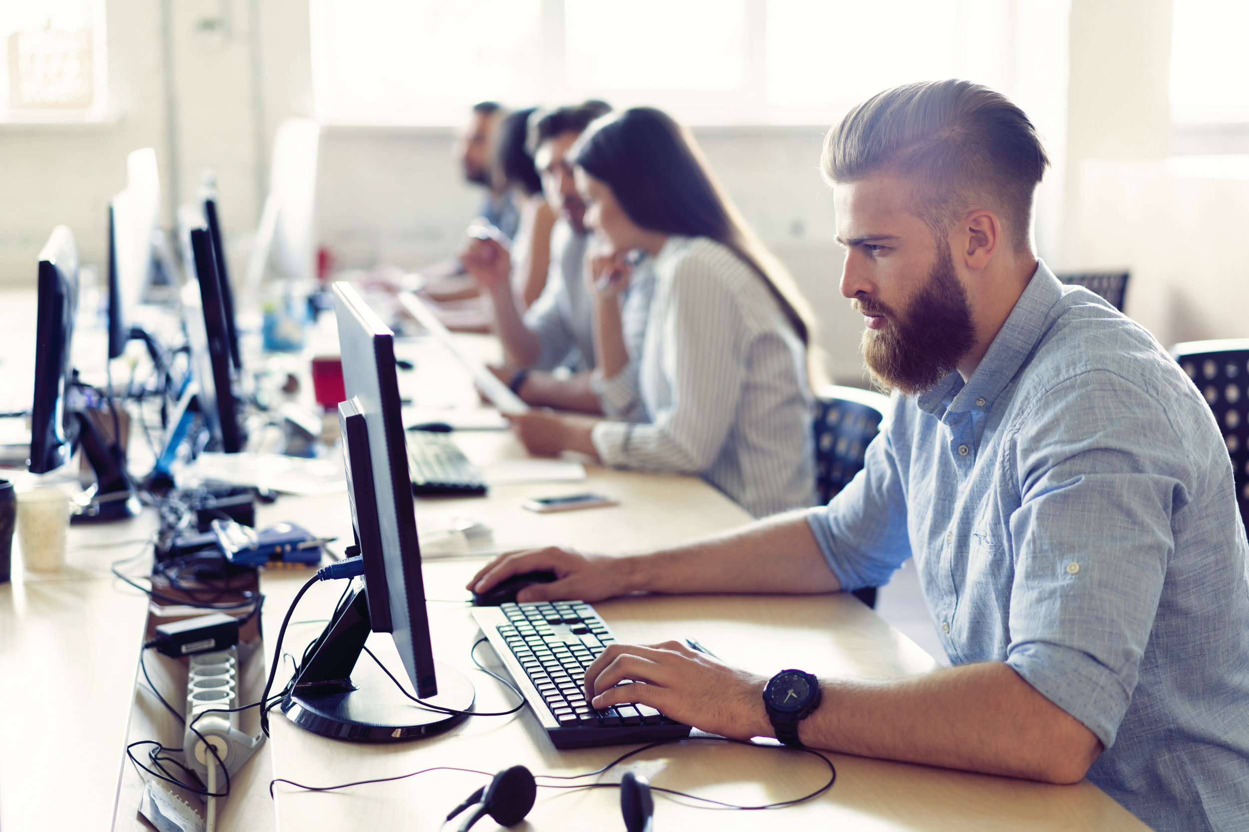 Canva - Colleagues Are Concentrated on Their Work, Finding the Solutions of Their Company Problems, Sitting at Work Places in a Row in Light Modern Office..jpg