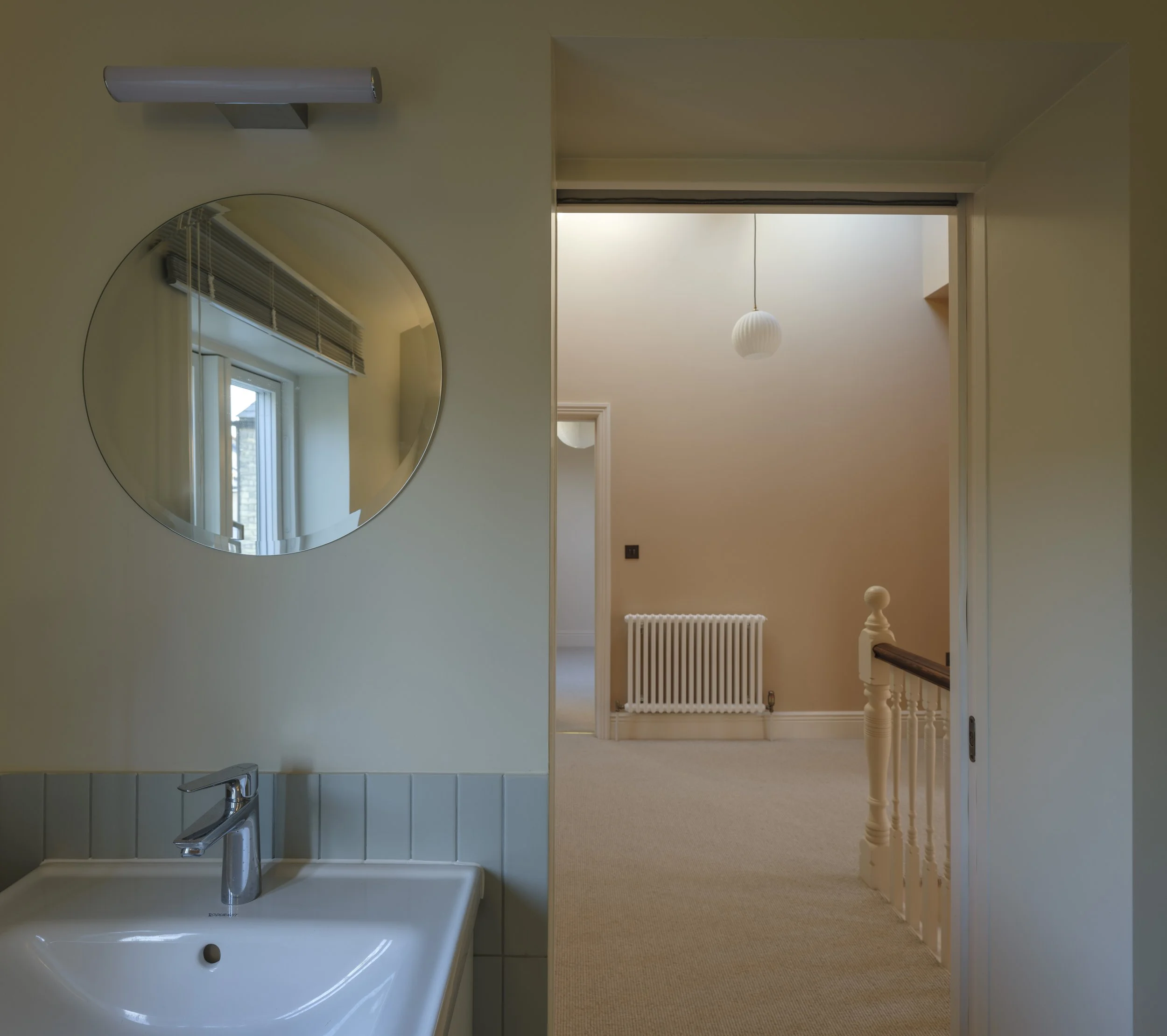 Side-by-side comparison of a bathroom sink with a mirror and a hallway with a radiator and a hanging light fixture.