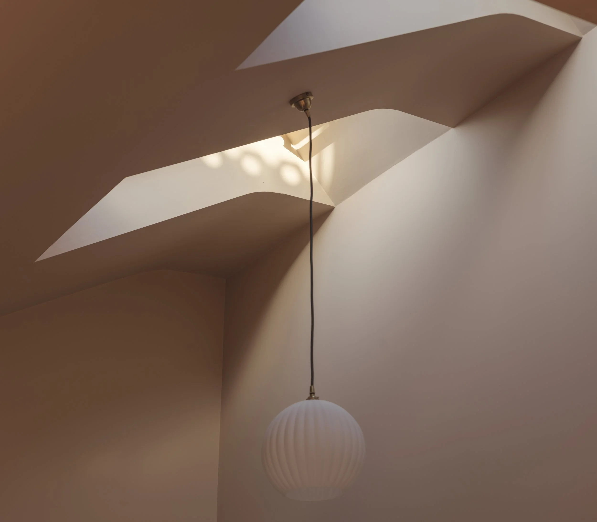 Ceiling with a hanging lamp and a skylight, with architectural curves and light shadows