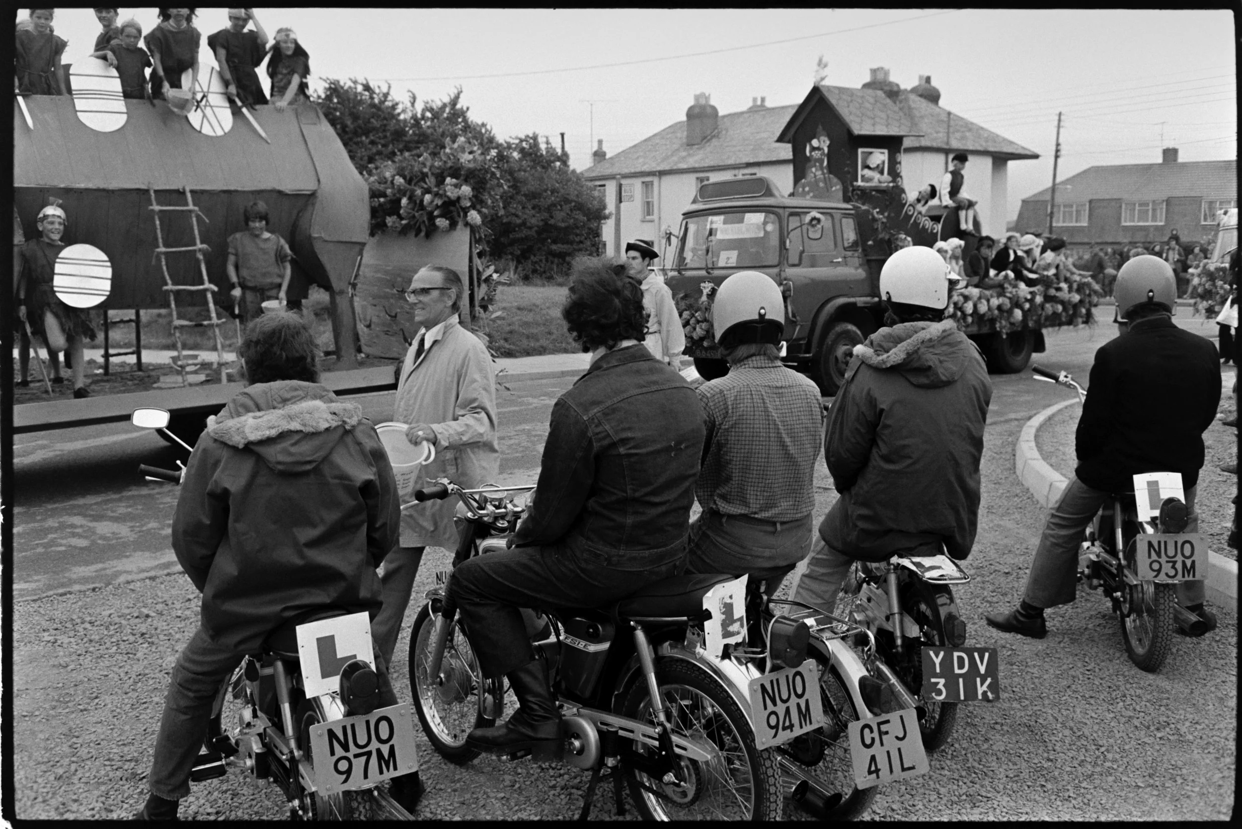 People on motorcycles watching the carnival float, Bideford, September 1973.