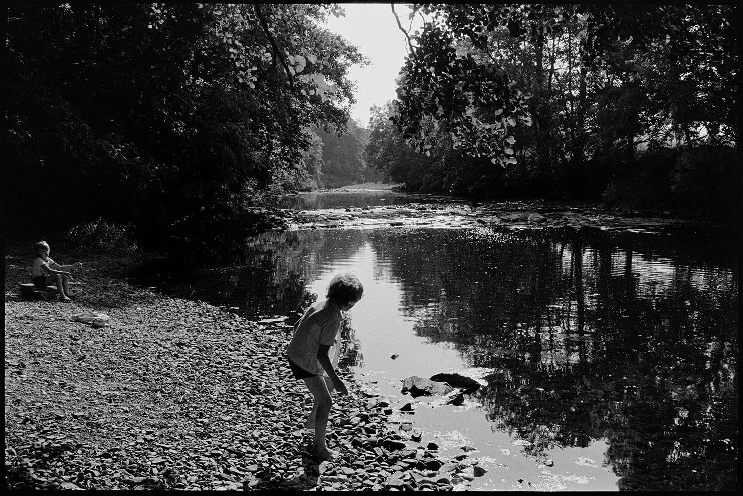 Children beside river, skimming stones Dolton, Halsdon, August, 1976.