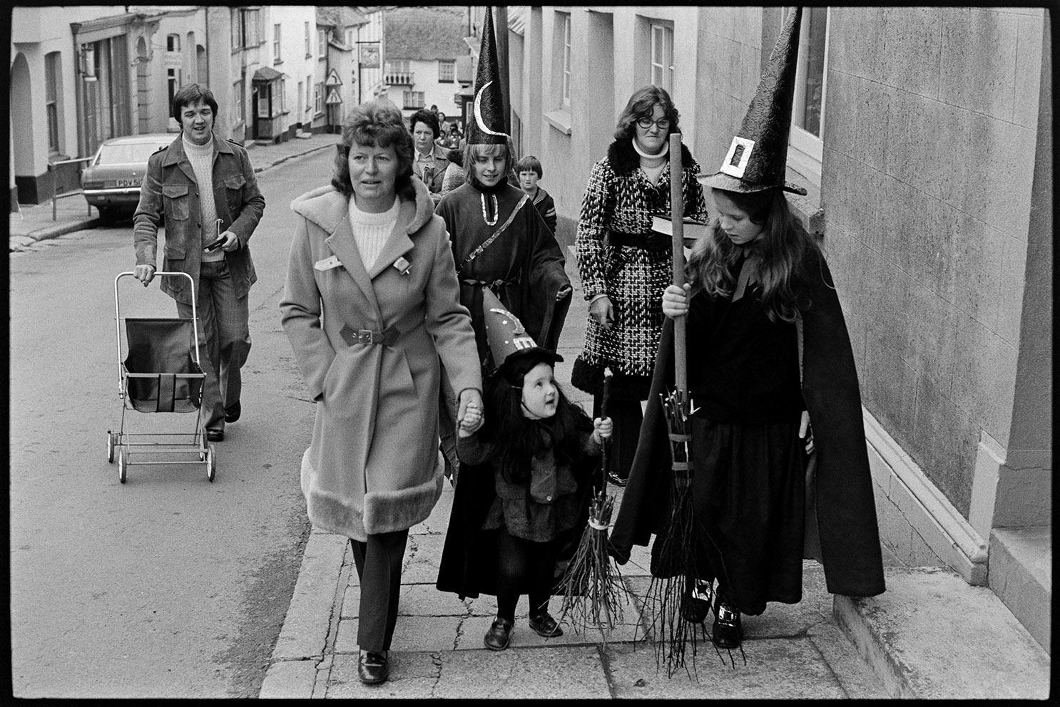 Girls dressed as witches and walking up the street, Hatherleigh, November 1975