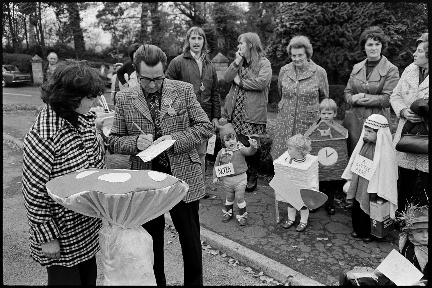 Man taking people's names for fancy dress competition, Hatherleigh, November 1975