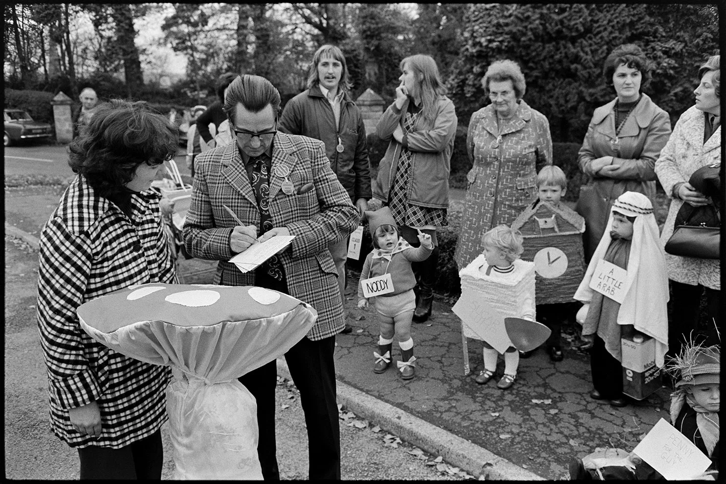 Man taking people's names for fancy dress competition, Hatherleigh, November 1975