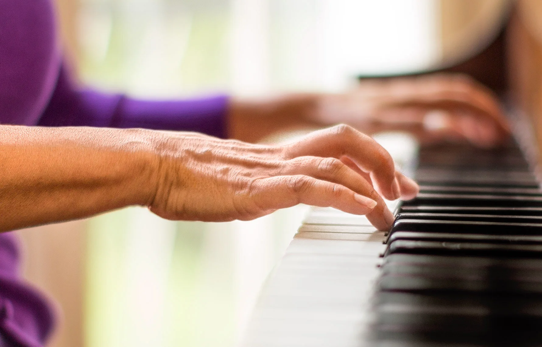 Detail image of hands playing piano for healthcare and pharmaceutical brand campaign.