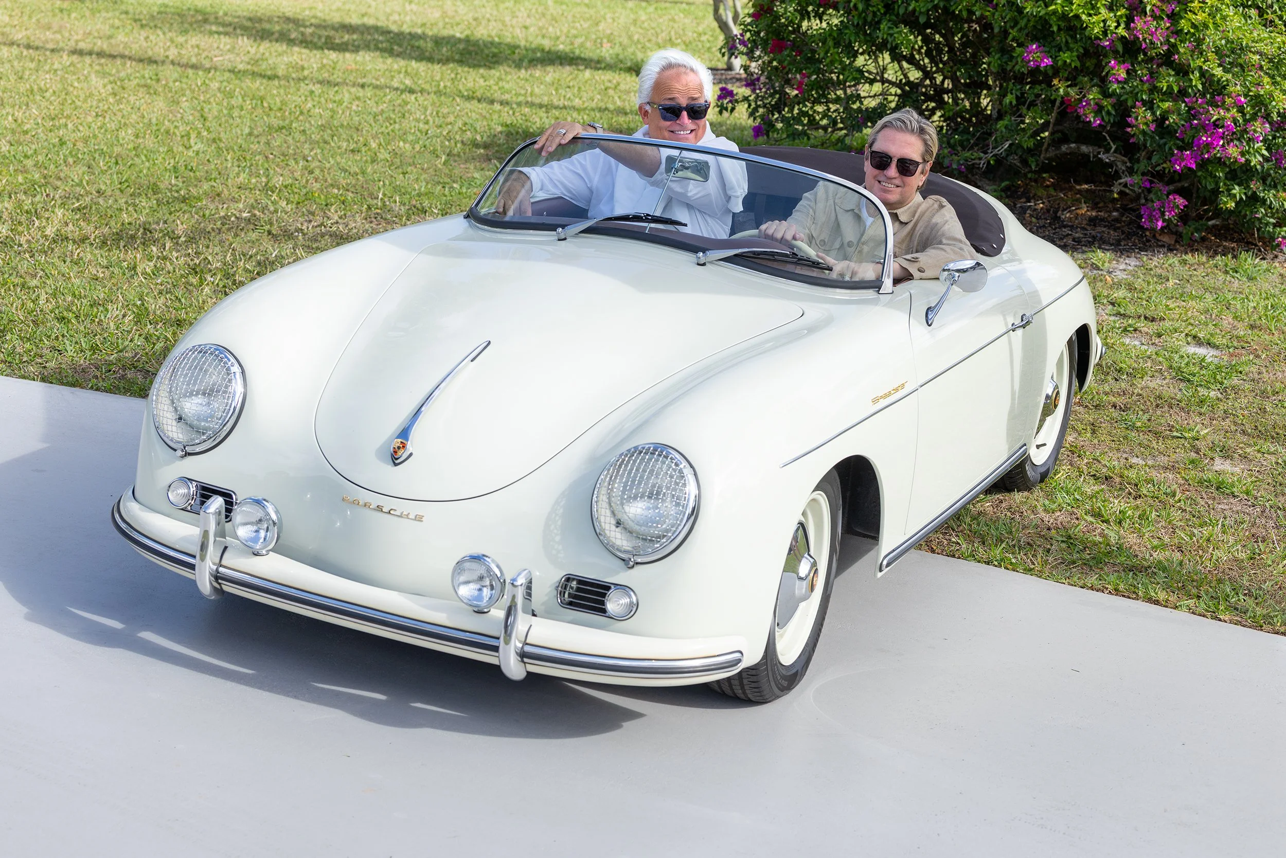Mark Badgley and James Mischka seated in a white vintage Porsche convertible at their South Florida home.
