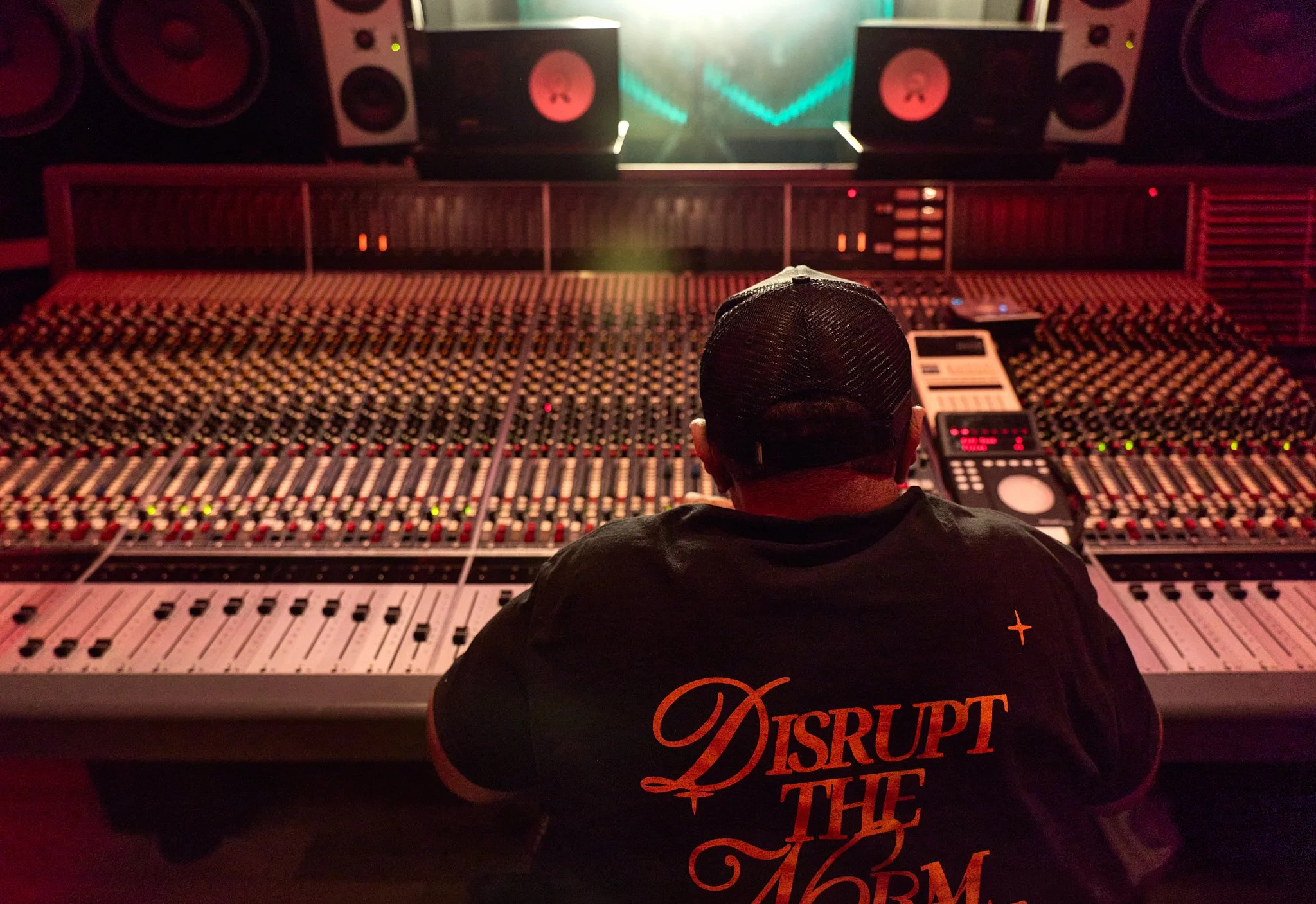 Timbaland seated at a large recording studio mixing console, photographed from behind.