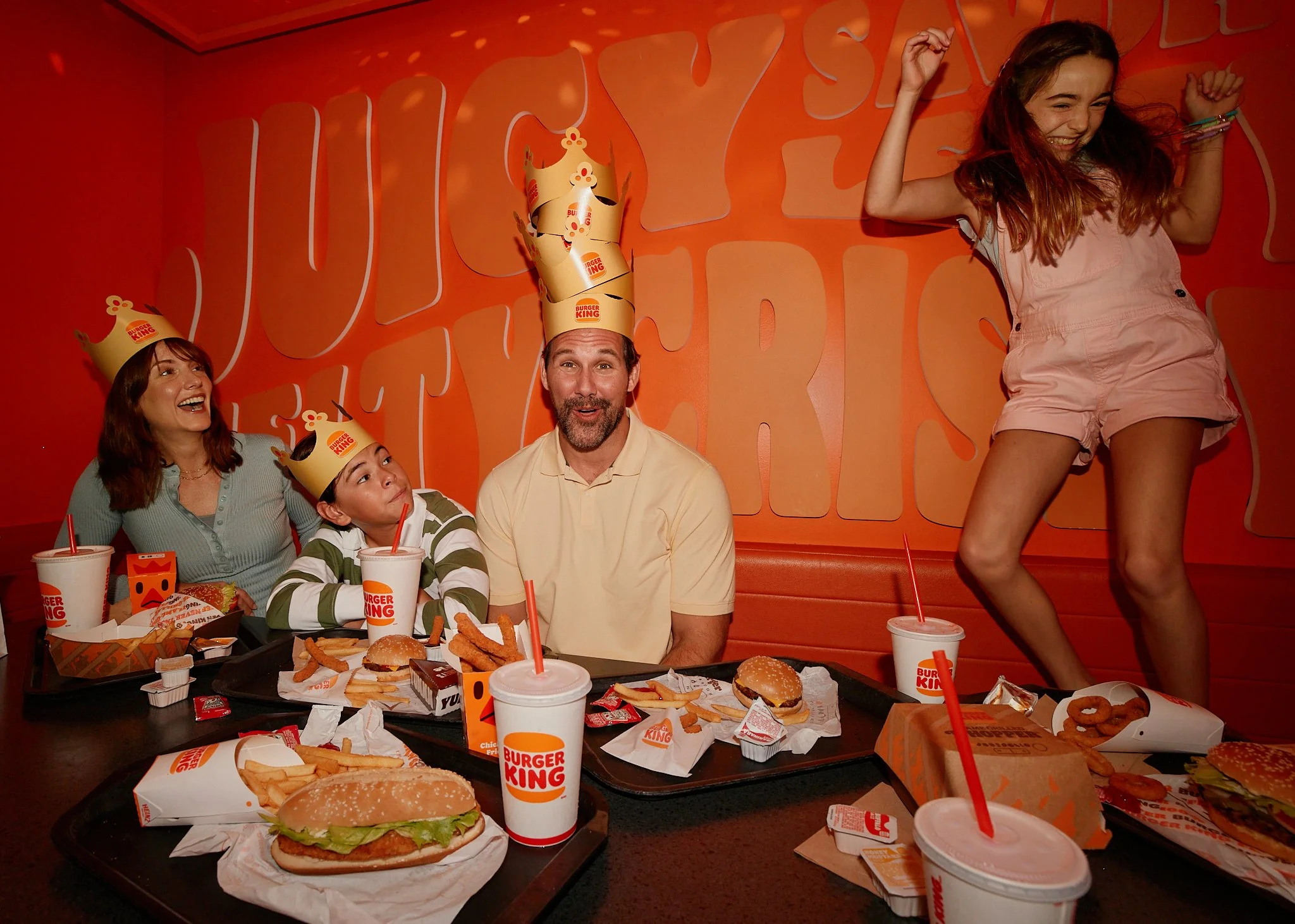 Family and friends celebrating around a Burger King table with crowns, burgers, fries and drinks.