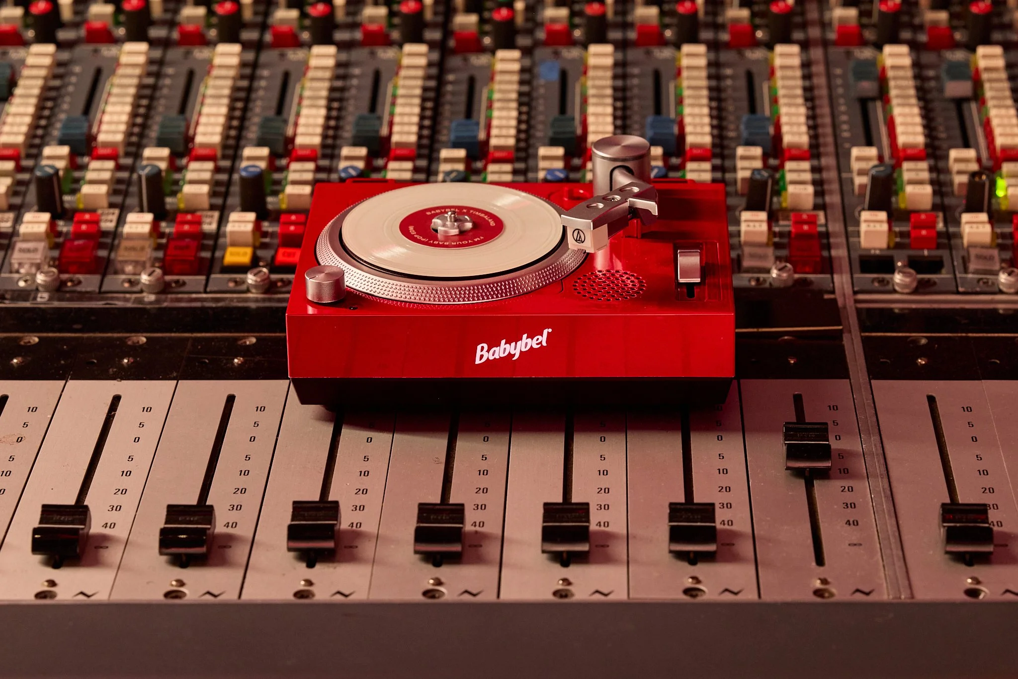 Red Babybel Wax Tracks miniature turntable displayed on a professional recording console.