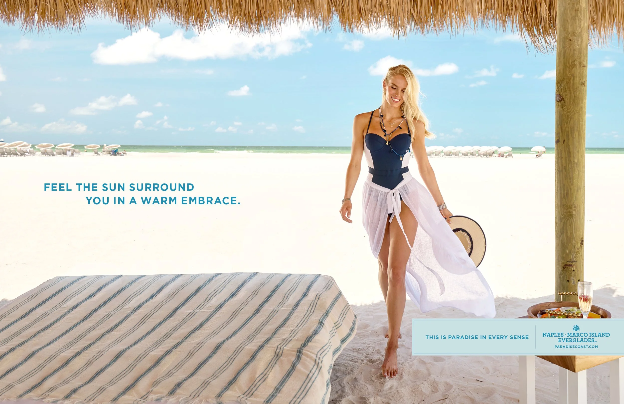 Woman walking across white sand beach beneath a cabana on Marco Island Florida — luxury beach lifestyle imagery from the Paradise Coast tourism campaign.