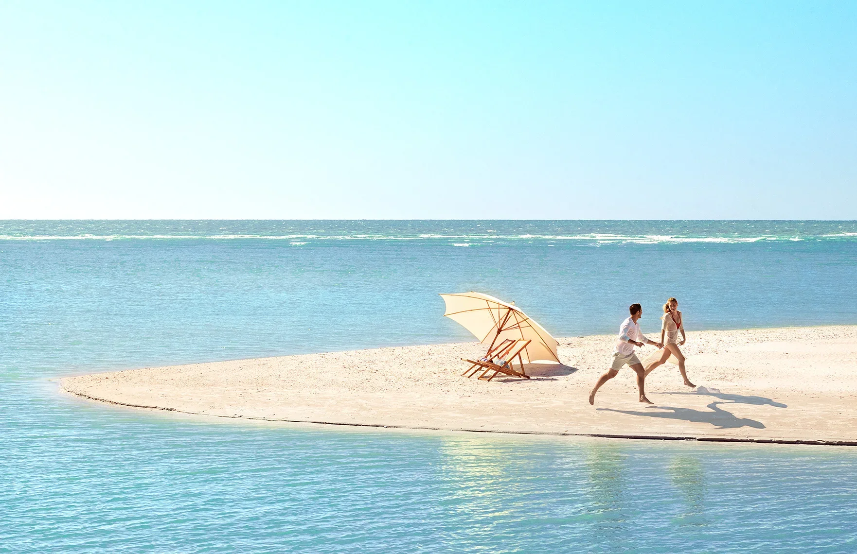 Couple running along a sandbar in turquoise water photographed for the Love, Paradise tourism campaign for Collier County Tourism in Naples and Marco Island Florida.