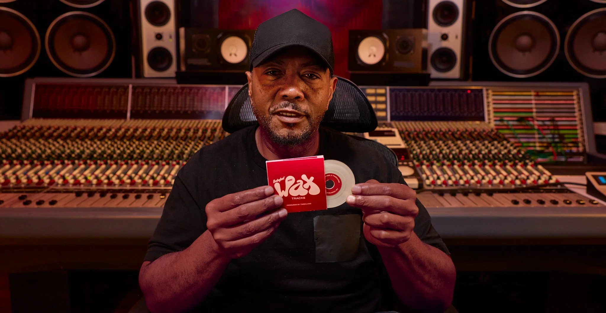 Timbaland holding a Babybel Wax Tracks miniature record and sleeve in the recording studio.