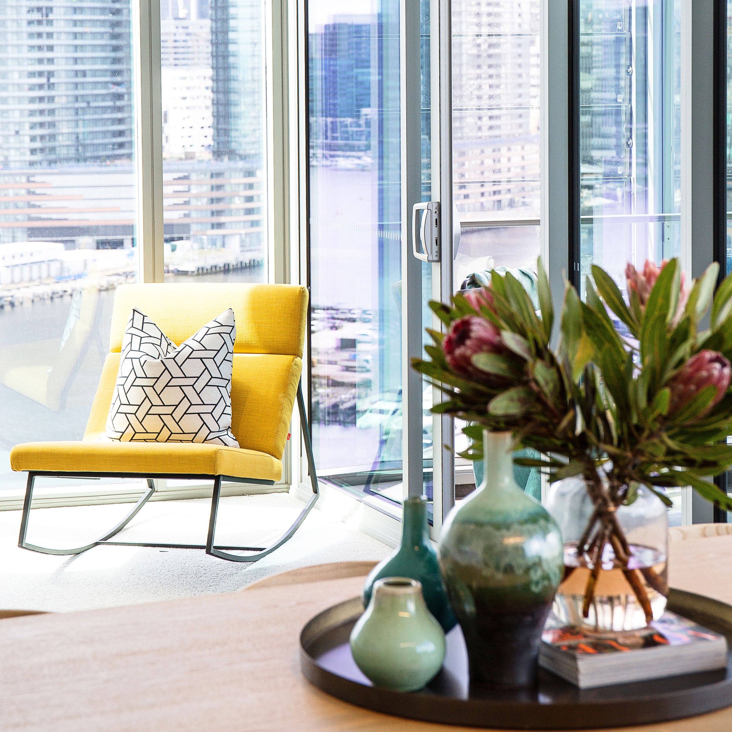 Interior styling detail of yellow lounge chair and geometric cushion in Mirvac Forge Docklands display apartment.