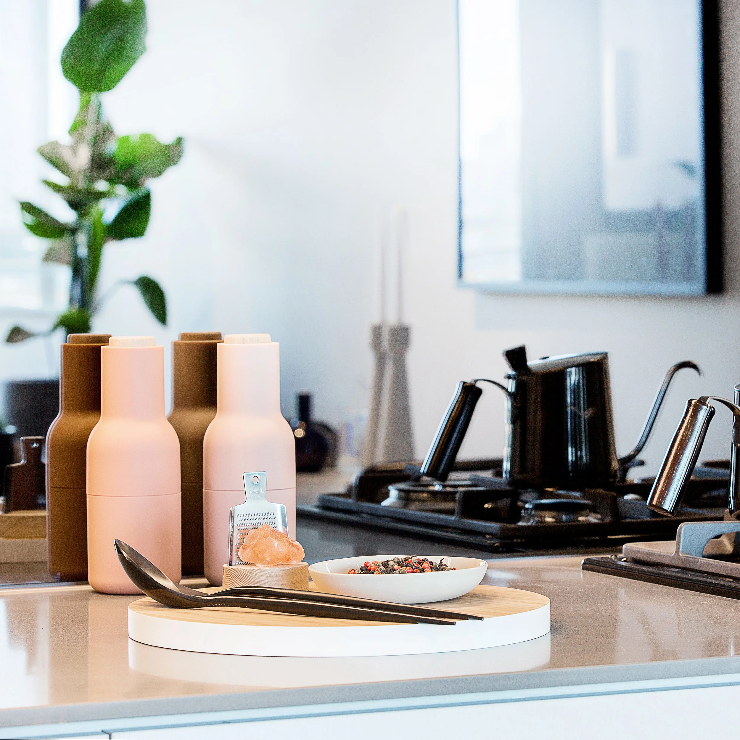 Styled kitchen vignette featuring sculptural vessels, cooktop detail and layered accessories to create warmth within a sleek loft interior.