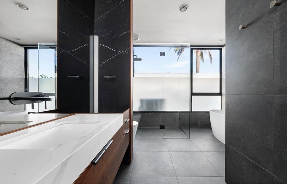 Close-up of timber vanity with inset stone benchtops and freestanding bath