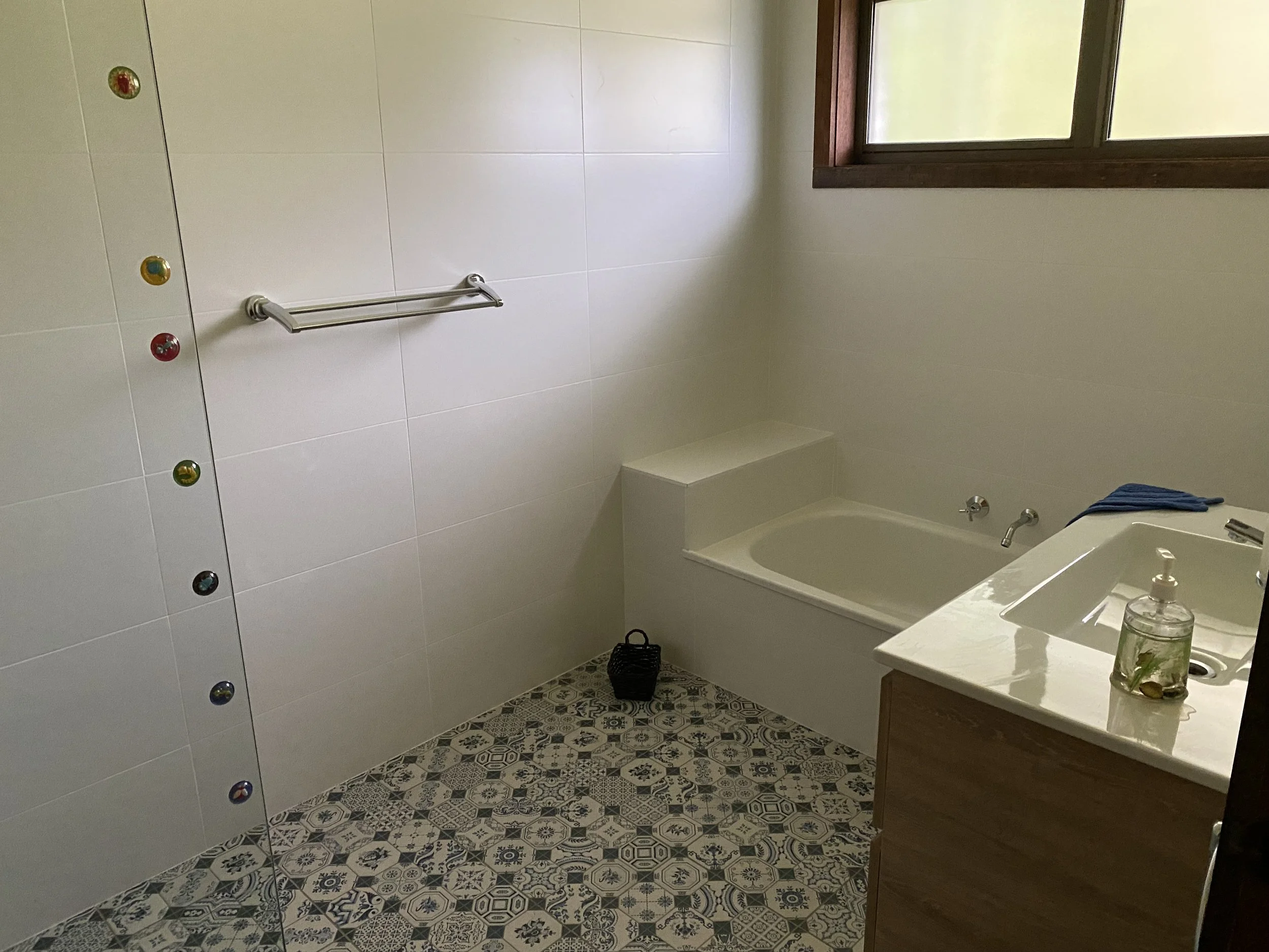 Dromana renovation before image of original bathroom with dated patterned floor tiles, built-in bath and basic vanity