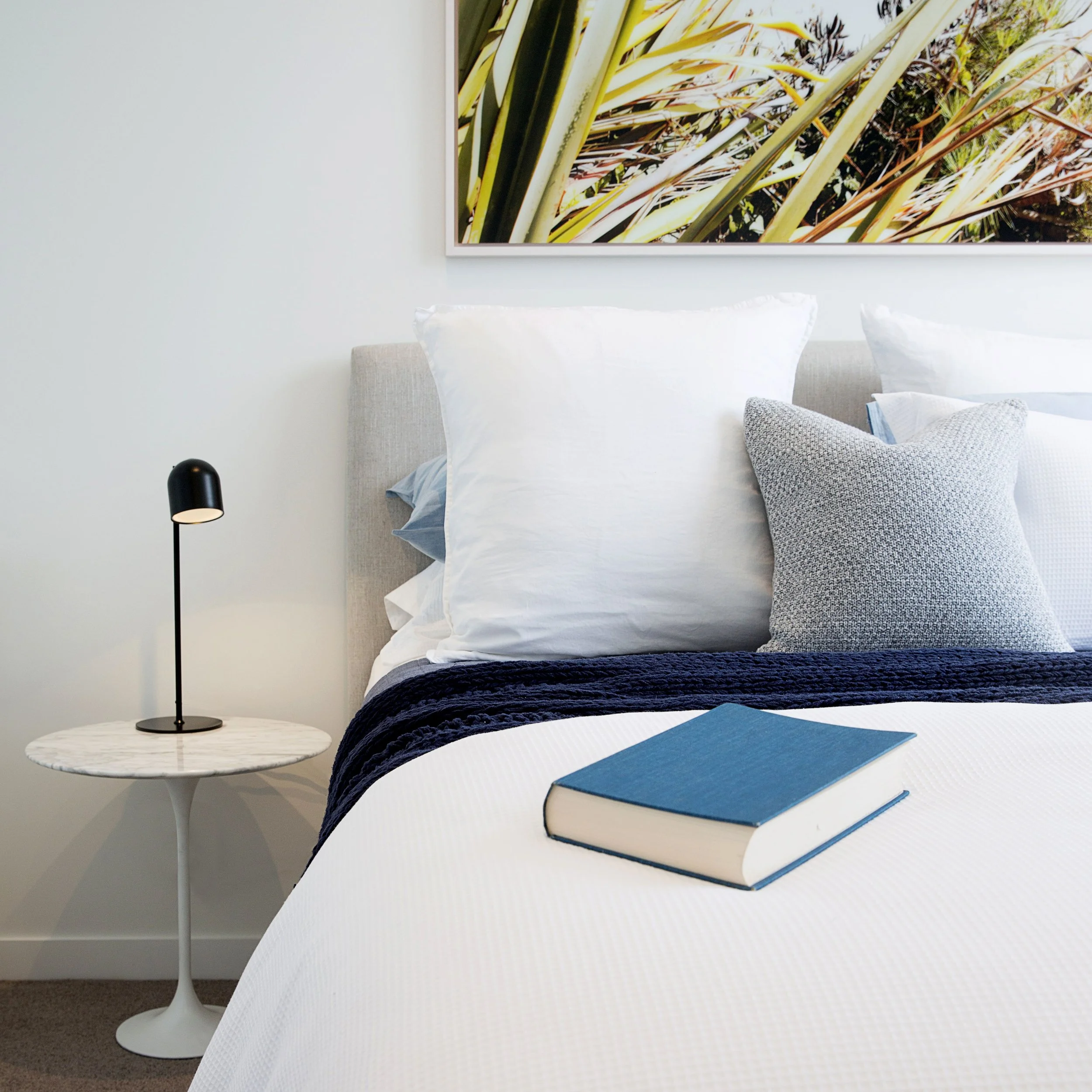 Main bedroom styling in a Docklands townhouse with upholstered bed, layered bedding and soft window furnishings