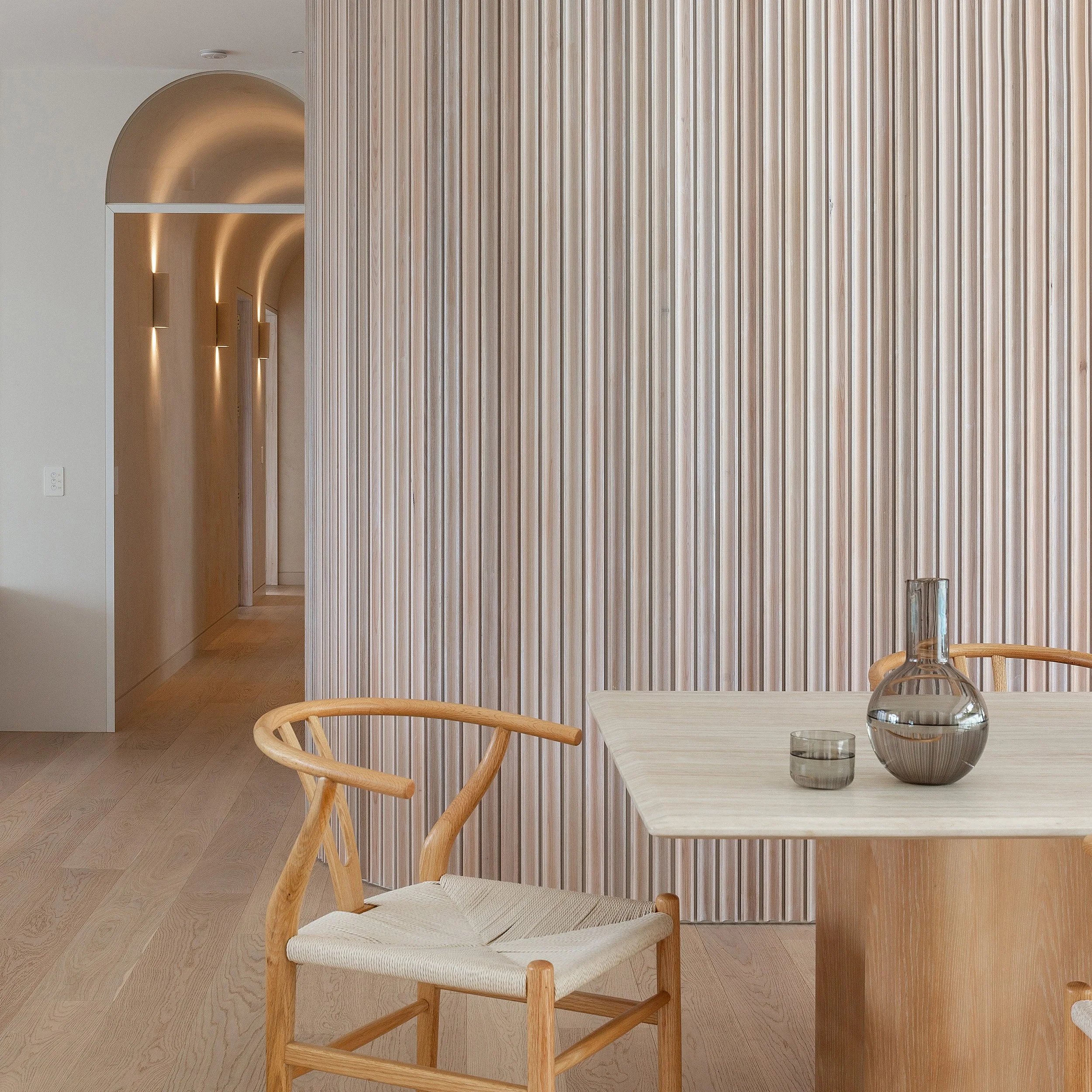 Lime washed panelled dining room wall with arched hallway