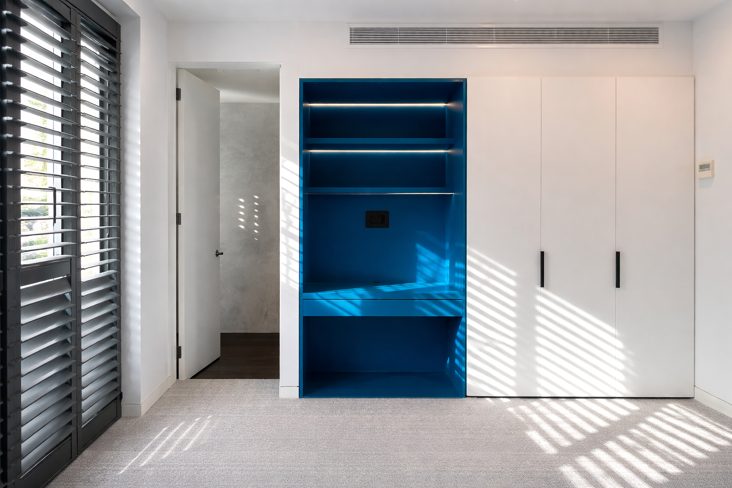Custom blue built-in study nook within white wardrobe cabinetry.