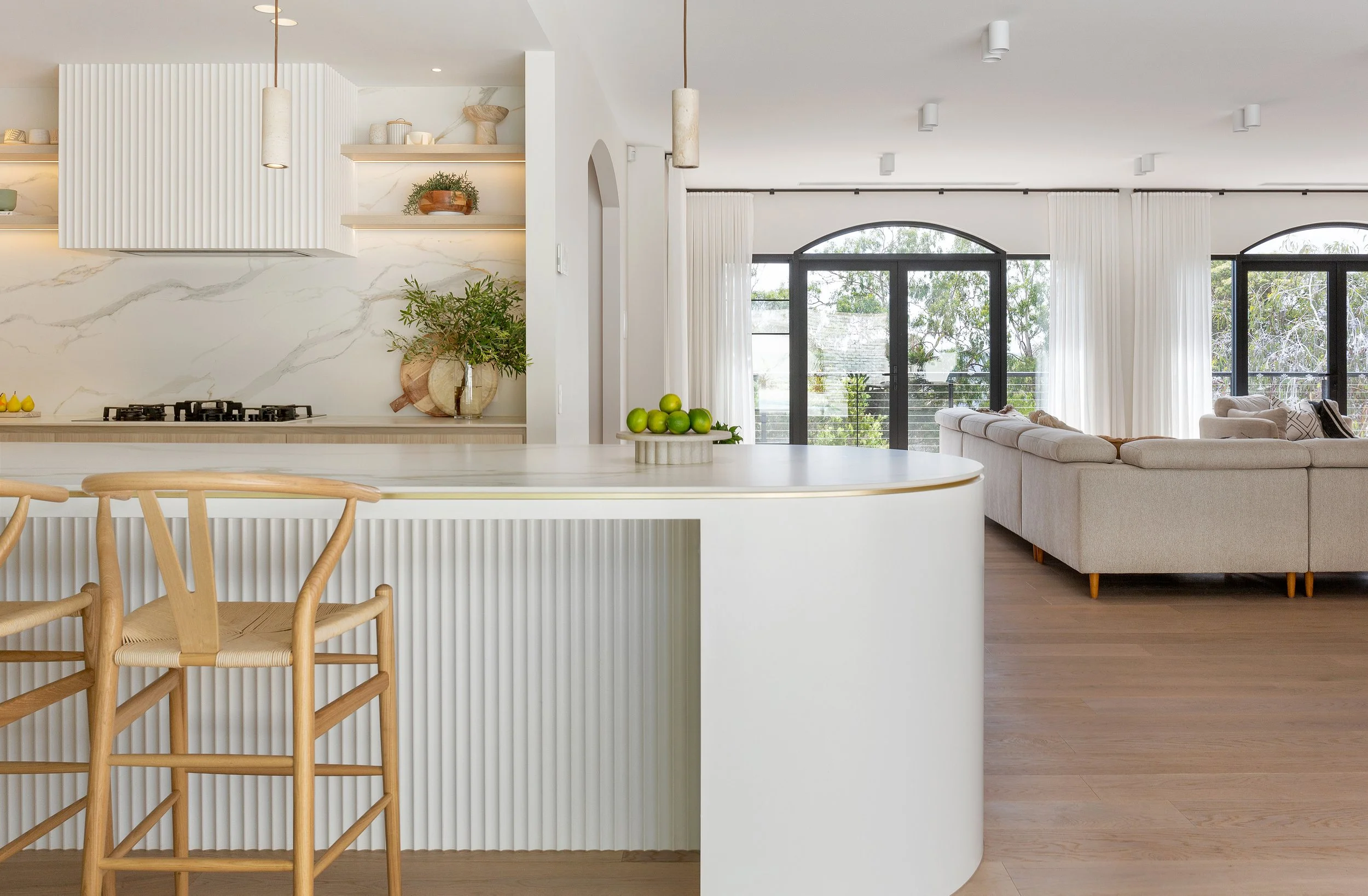 Kitchen and living space at Dromana residence with marble island, fluted joinery and arched black-framed windows