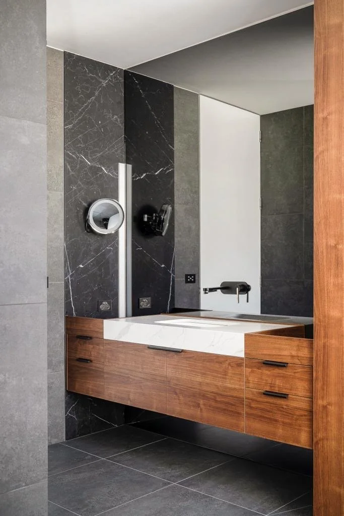 Close-up of timber vanity with inset stone benchtops, undermount basin and black handles