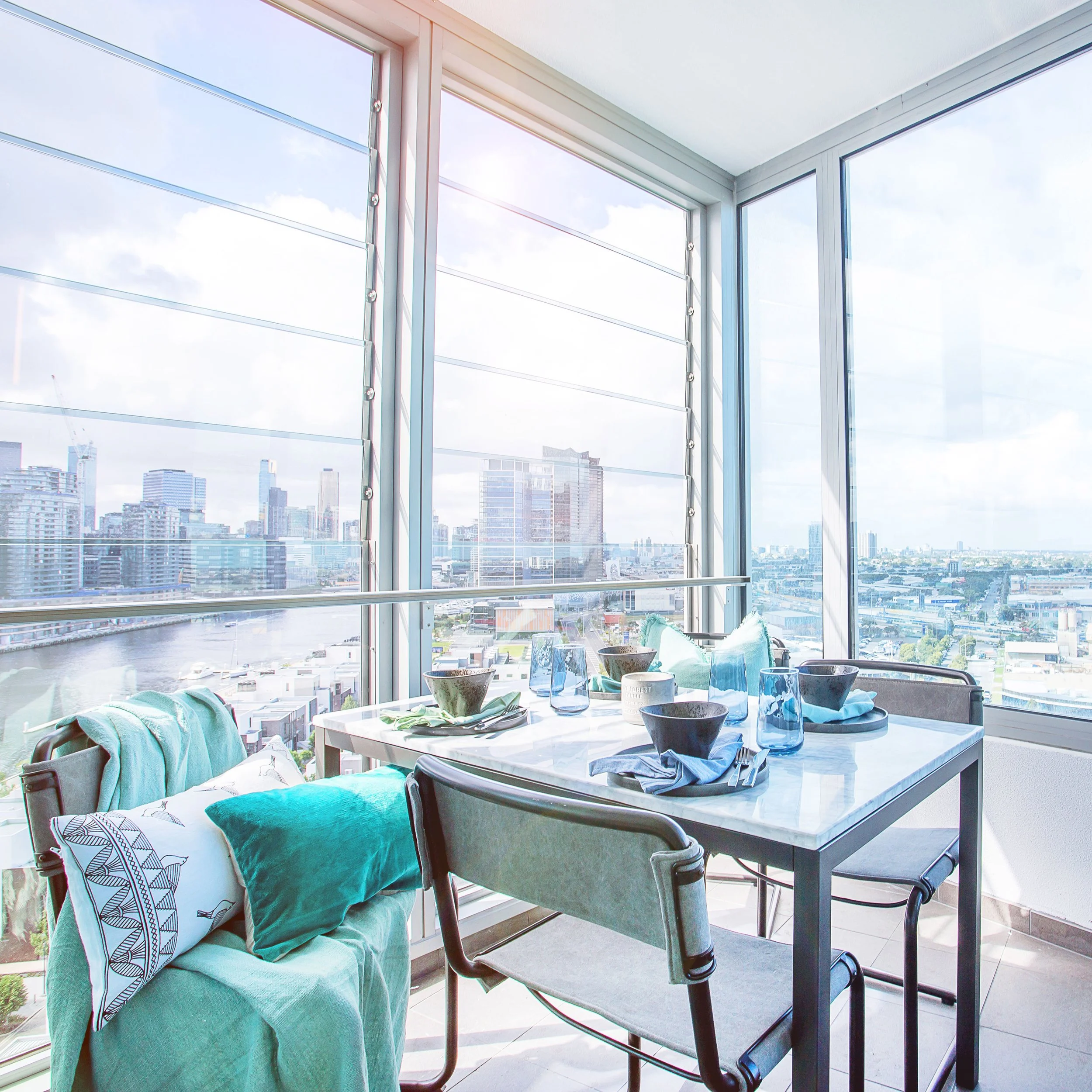 Enclosed winter garden balcony at Forge Docklands styled as dining space with river and city skyline views.