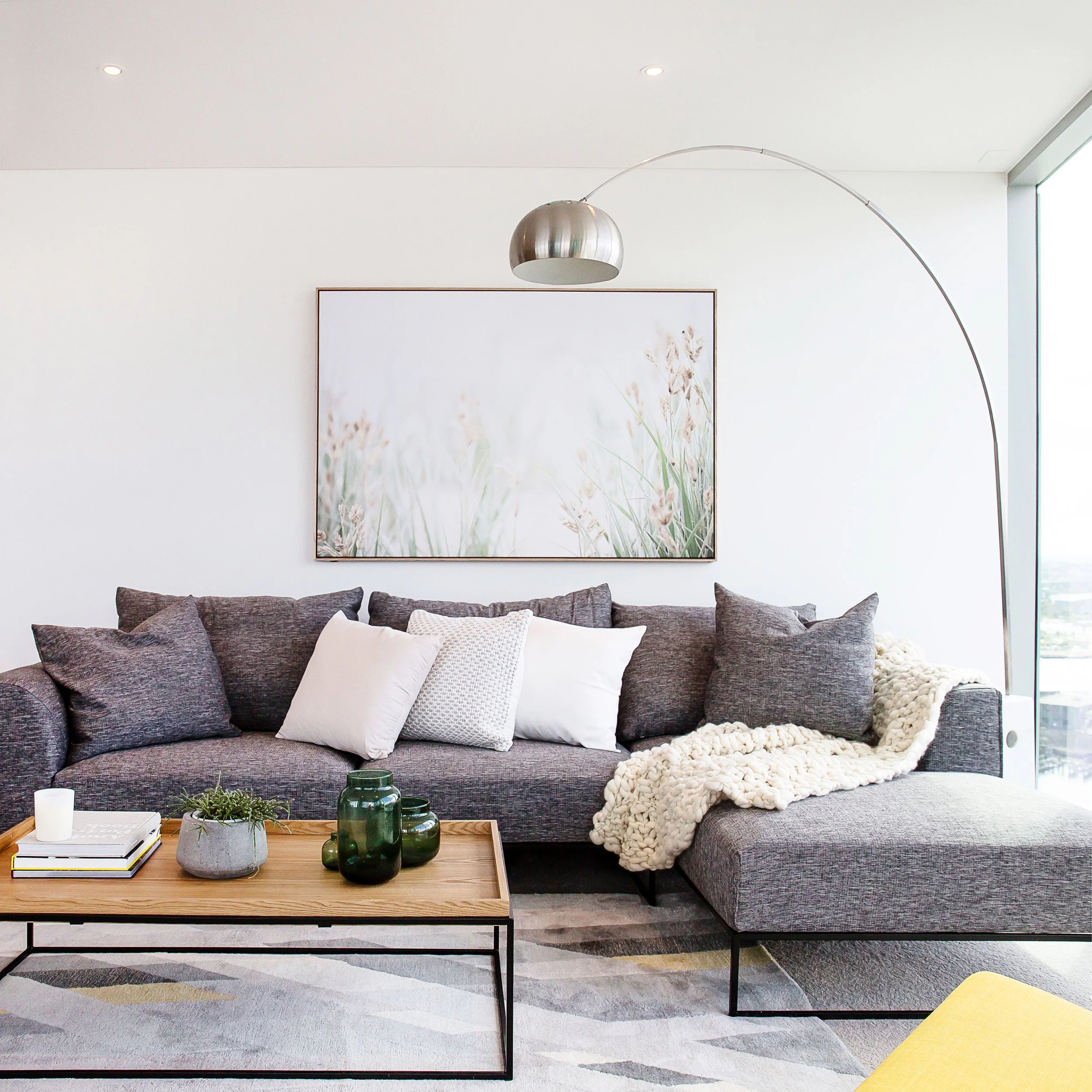 Open plan living area at Forge Docklands featuring floor to ceiling glazing, Yarra River views, artwork and contemporary styling by DMP Creative.