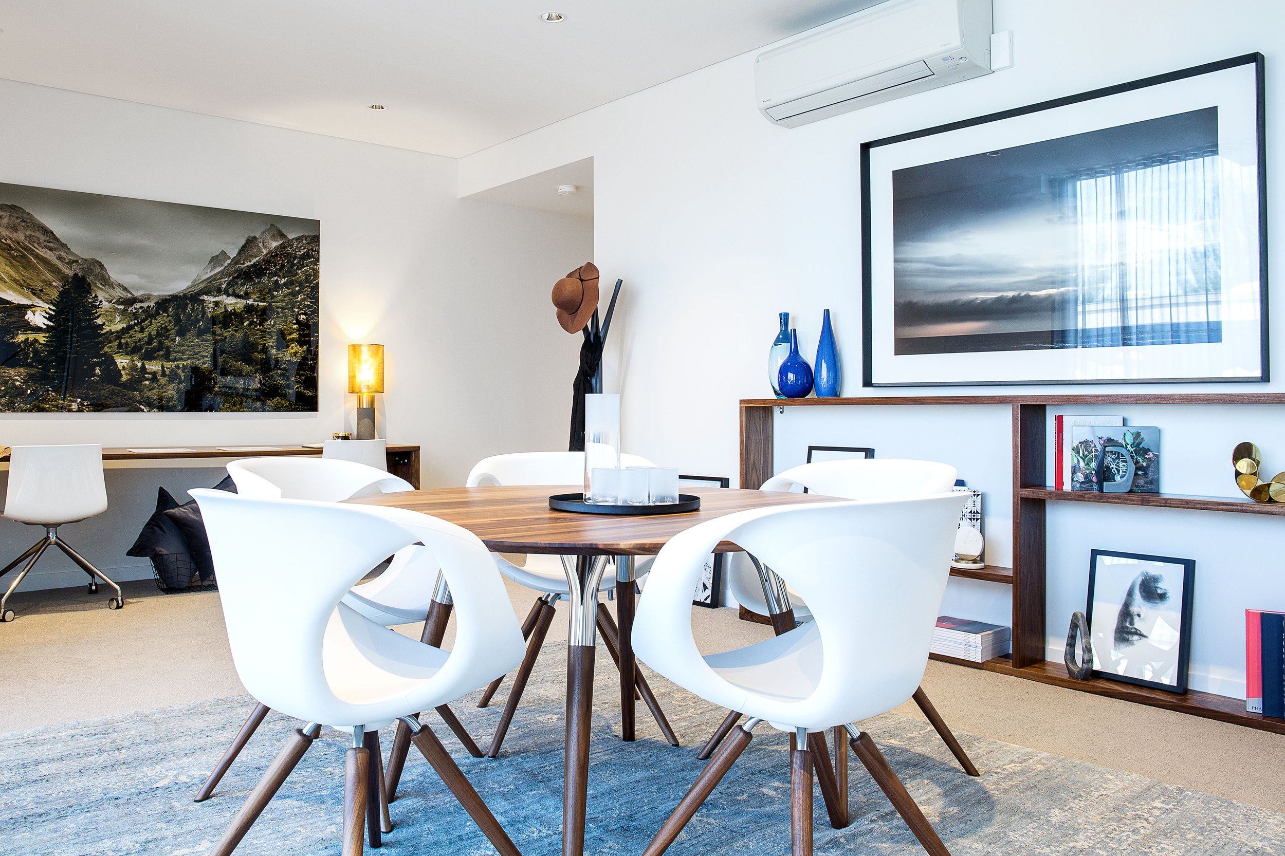 Contemporary home office featuring a conference table, built-in timber shelving and custom desk workspace