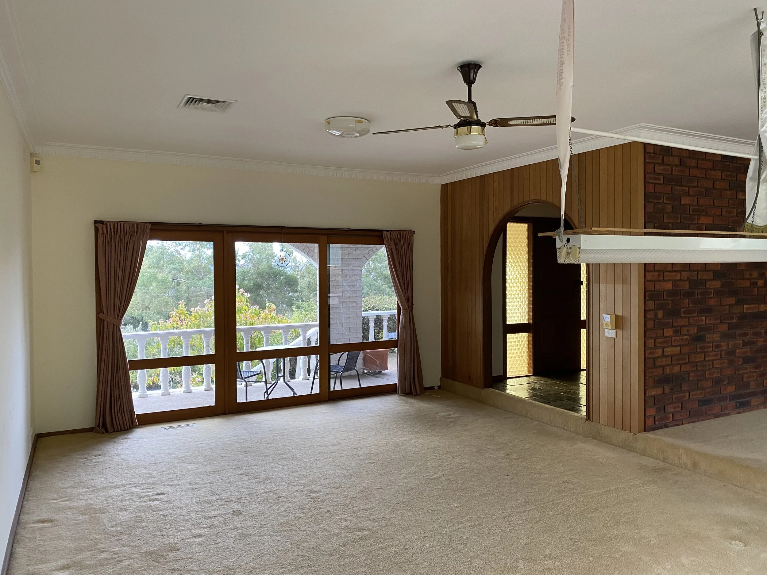 Dromana renovation before image of carpeted living room with timber panelling and large windows