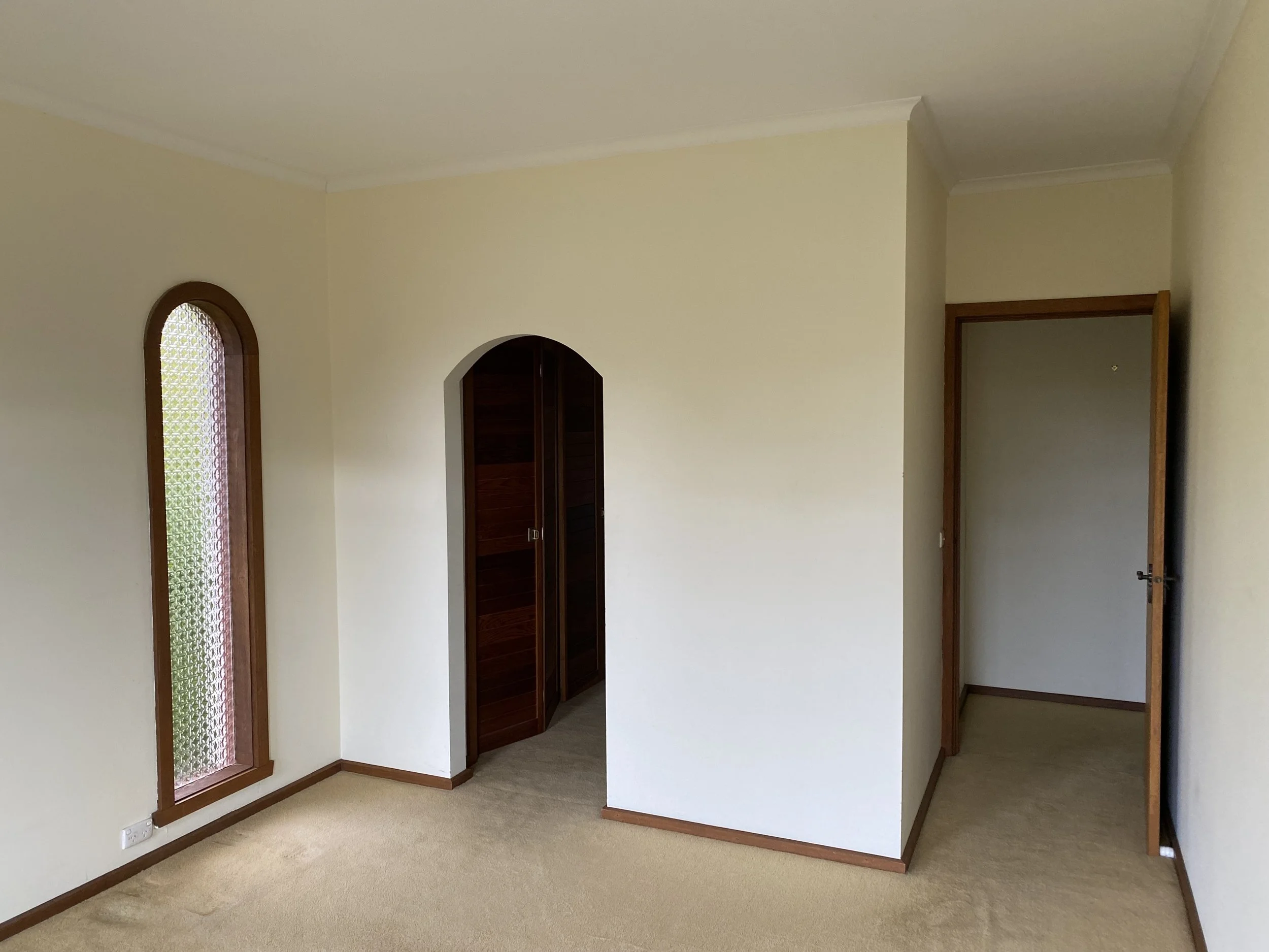 Dromana renovation before image of bedroom with arched doorway, built-in robe and original carpet flooring