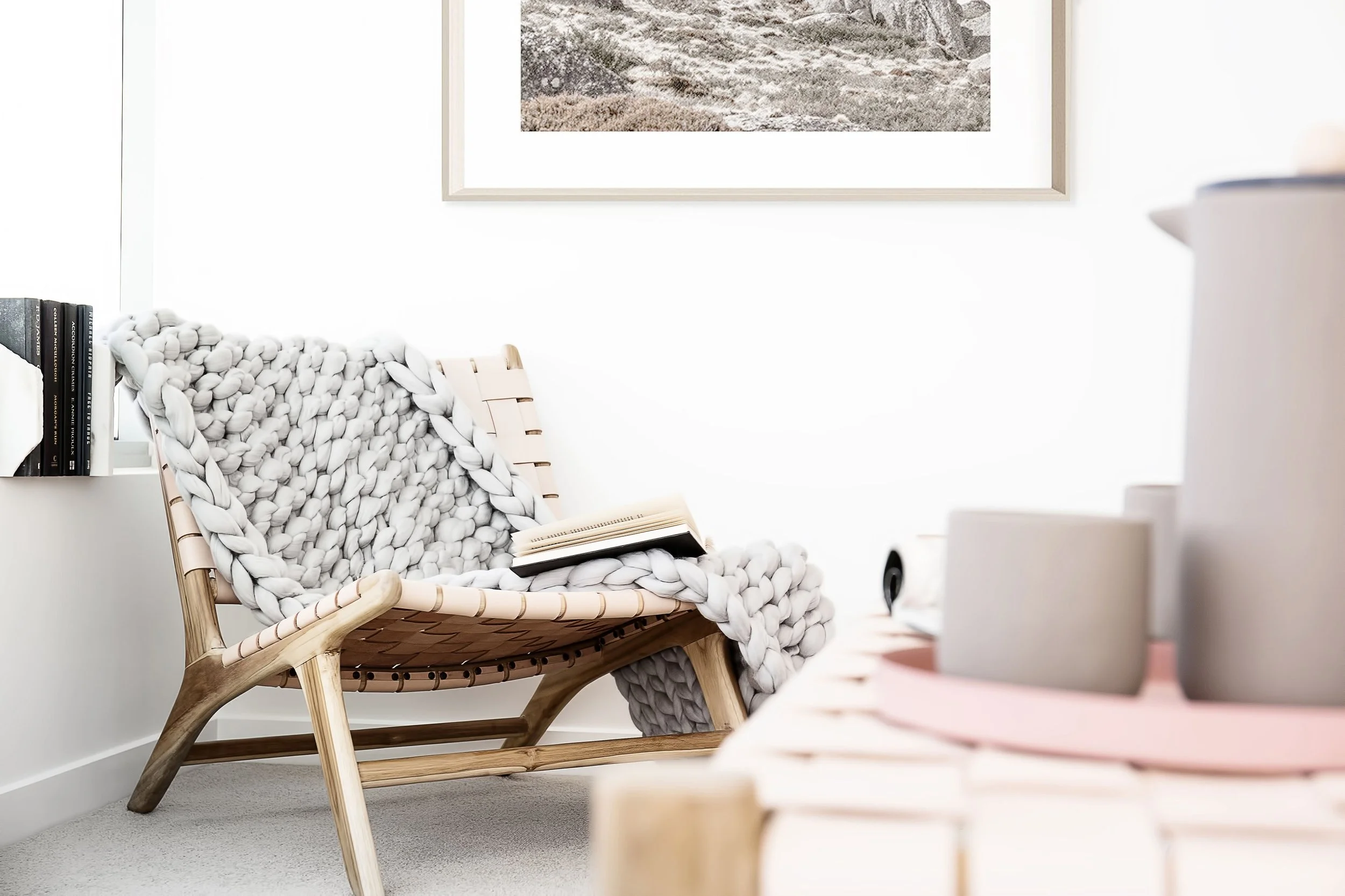 Timber lounge chair with chunky knit throw and book styling in Docklands apartment bedroom by DMP Creative.