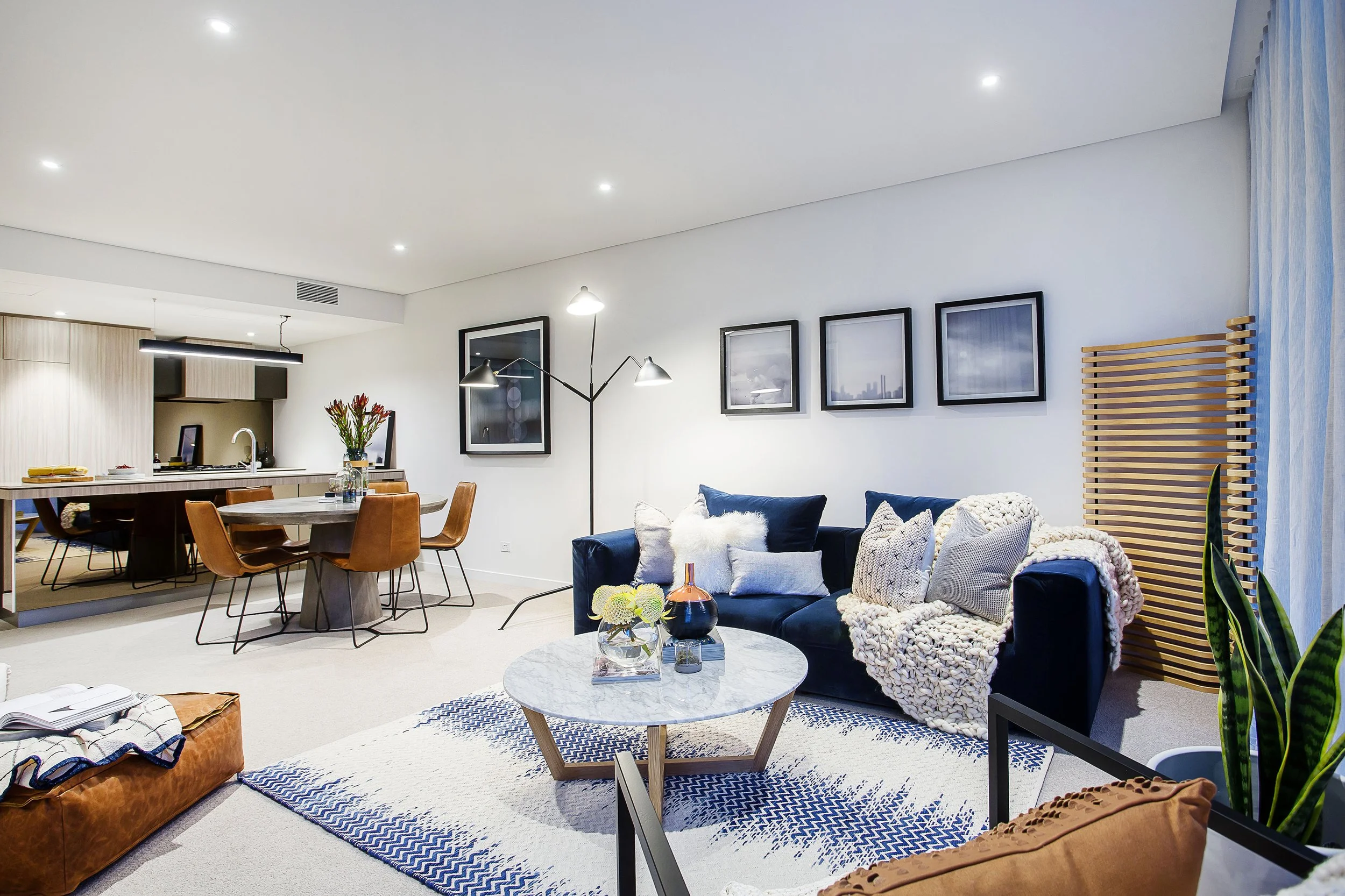 Navy upholstered sofa styled with textured cushions and knit throw in Apartment 204 at Forge Docklands.