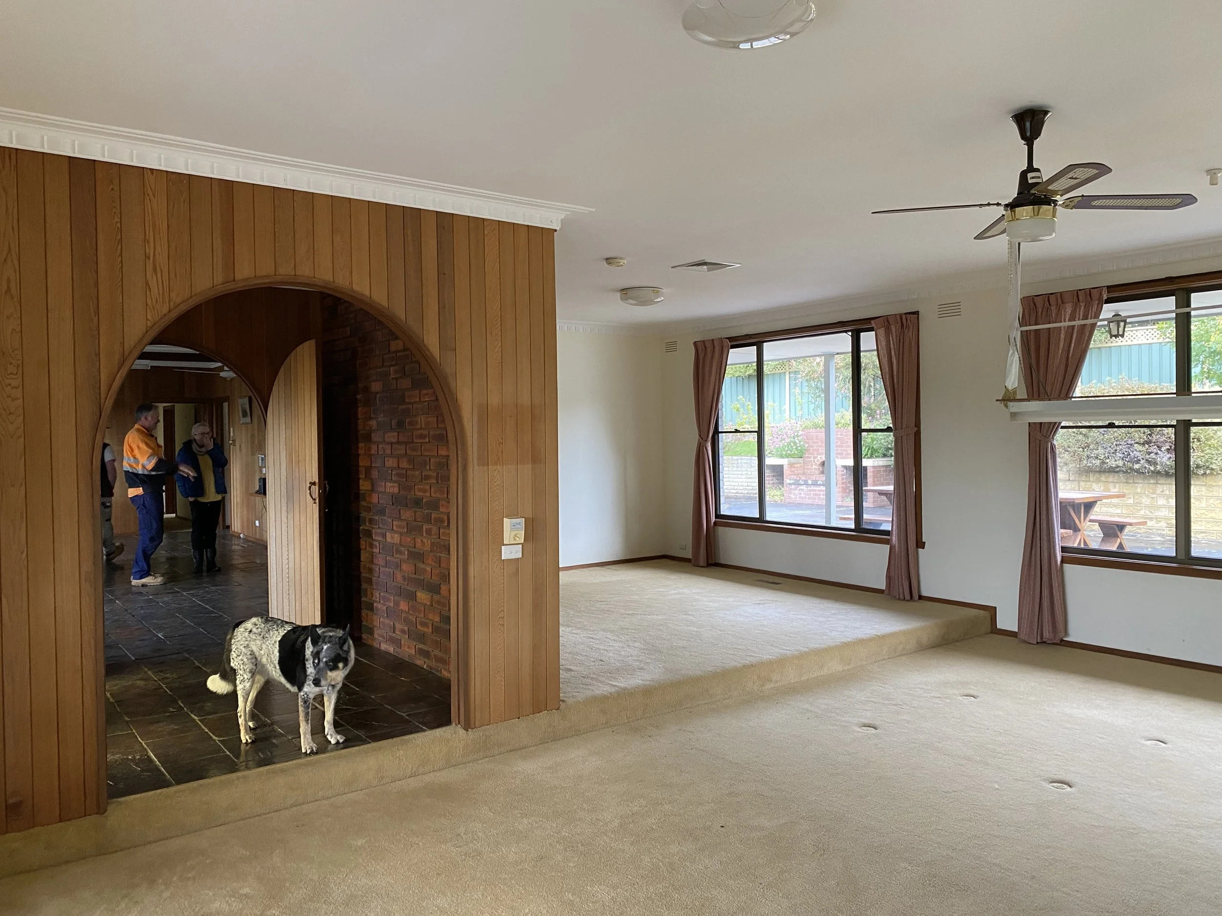 Dromana renovation before image of split-level living area with carpet flooring, dated finishes and garden outlook