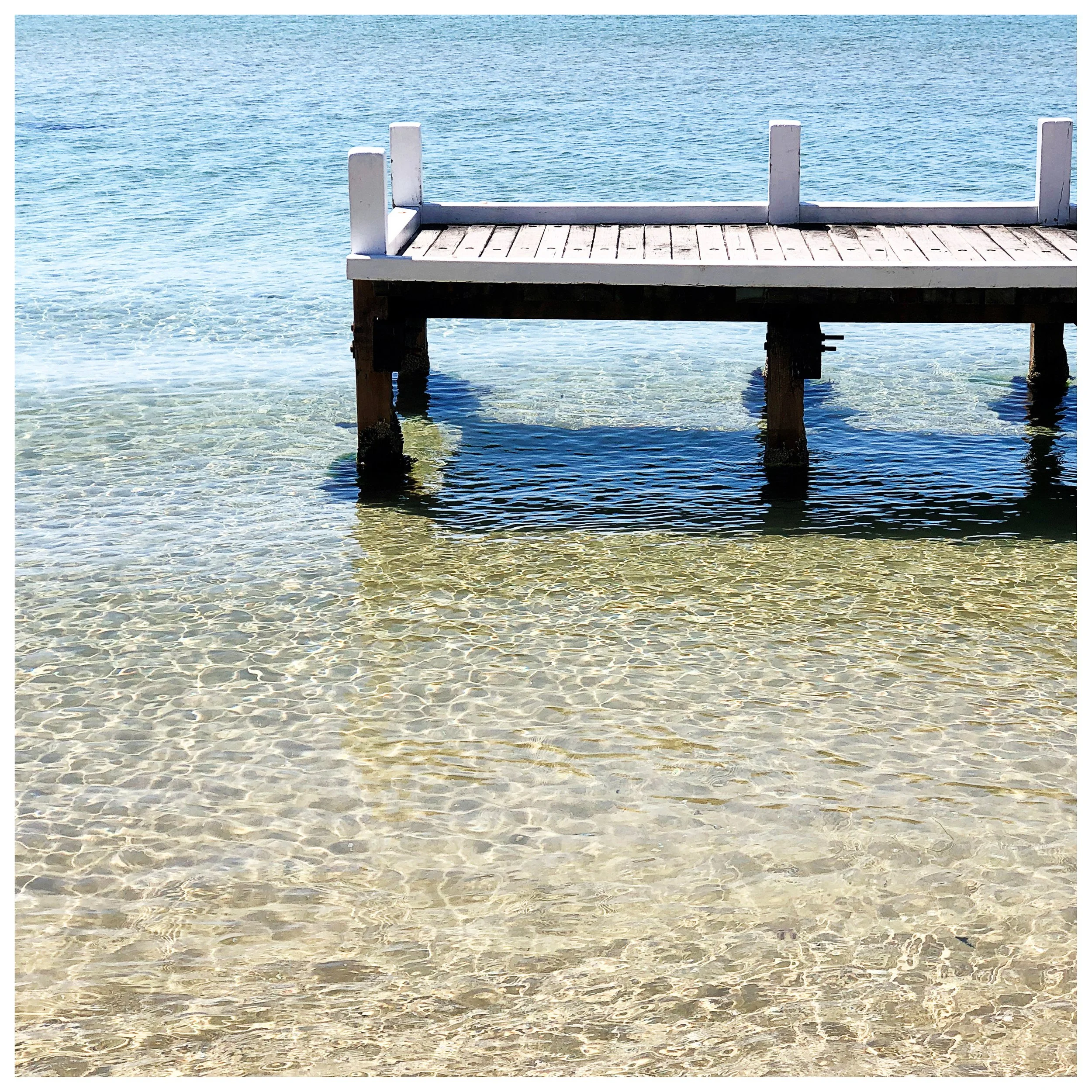 Timber jetty extending over clear shallow water in Sorrento, Victoria, capturing relaxed coastal holiday home atmosphere and seaside lifestyle