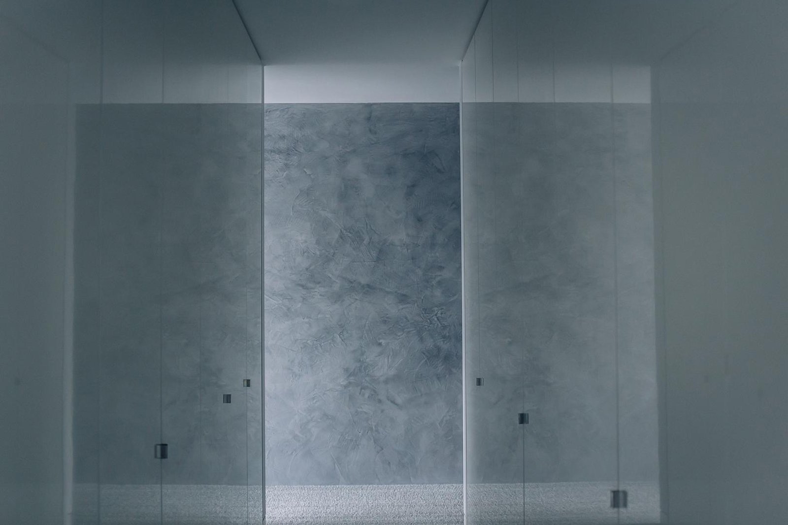 Bedroom with gloss white wardrobes and venetian plaster feature wall