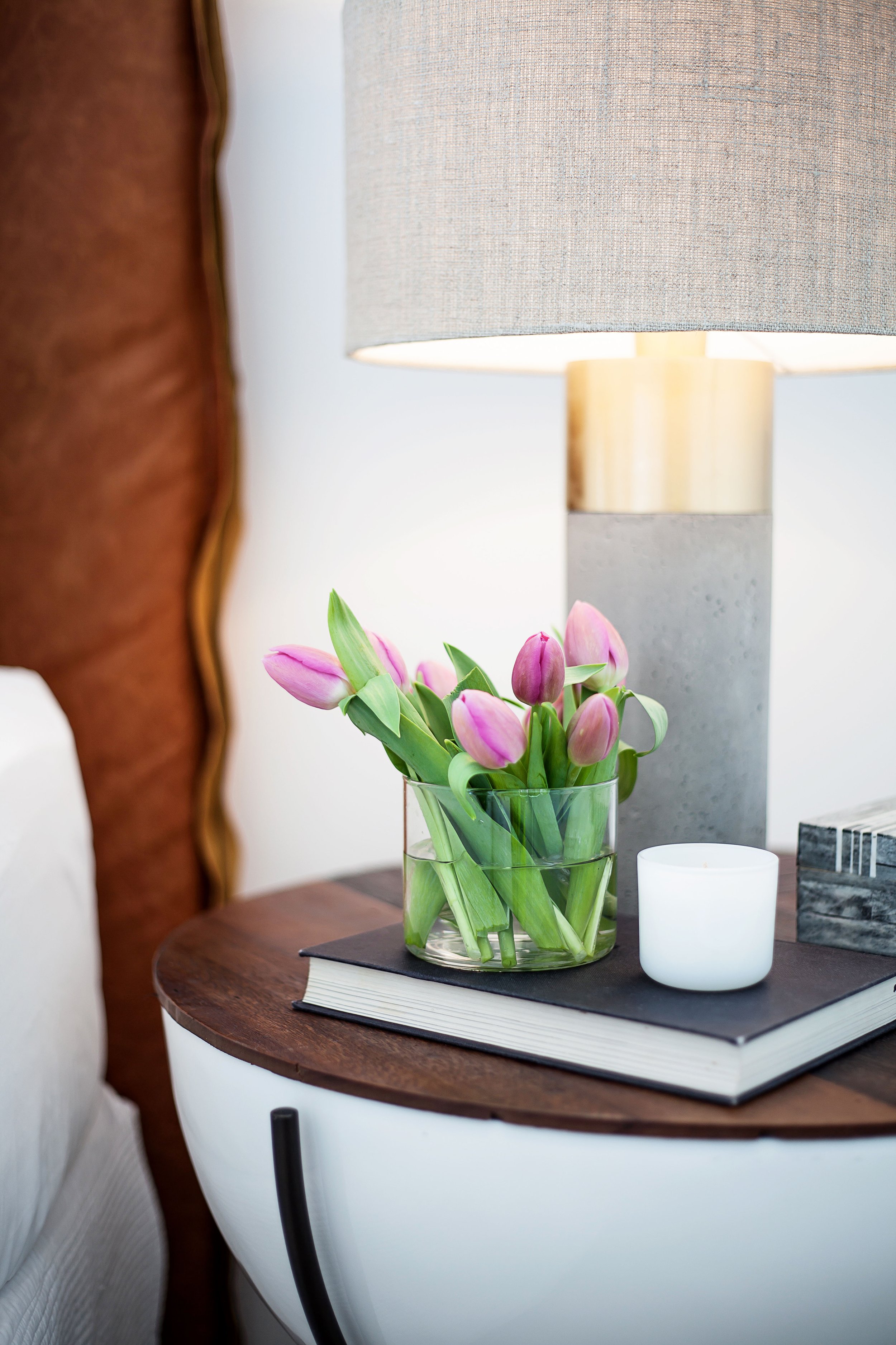 Bedside table styling detail in Forge Docklands Apartment 204 with curated accessories, flowers and concrete lamp
