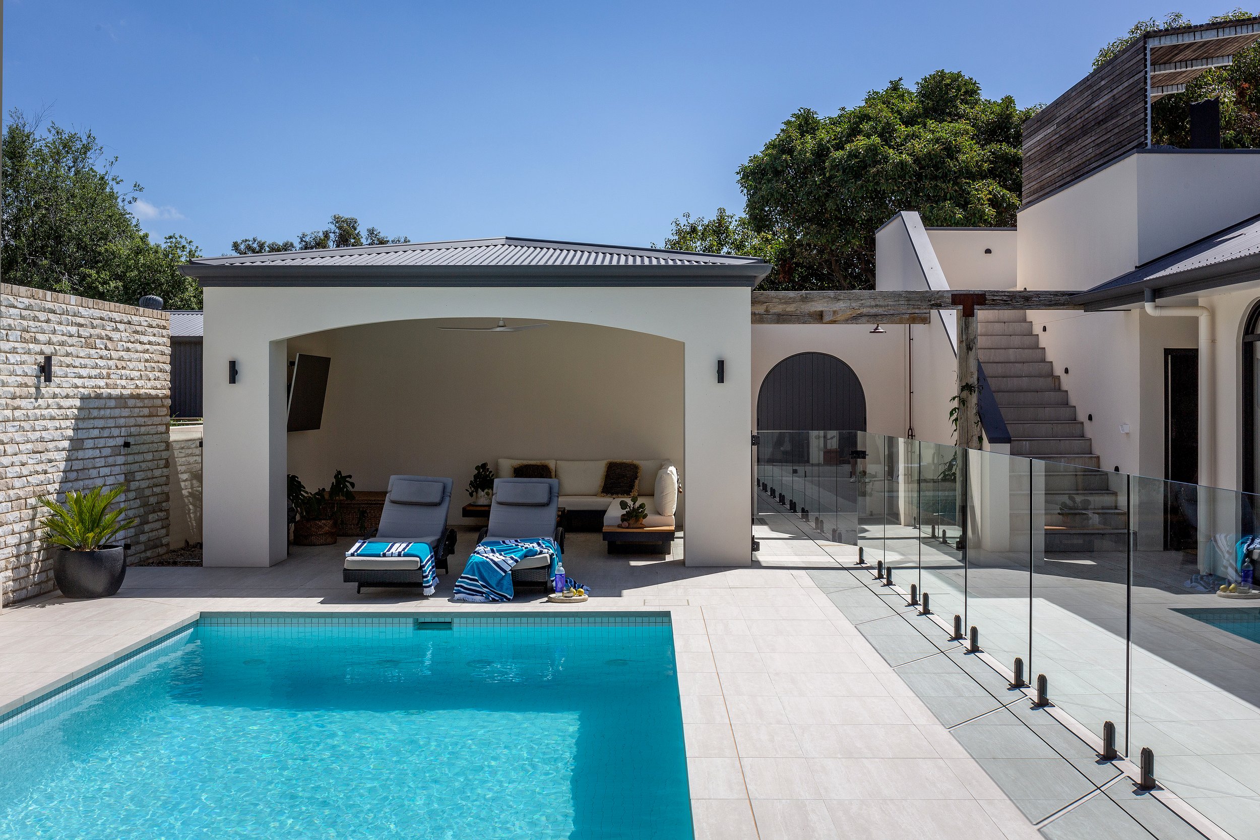 Outdoor pool area at Dromana residence with cabana, glass pool fence and coastal-style entertaining space