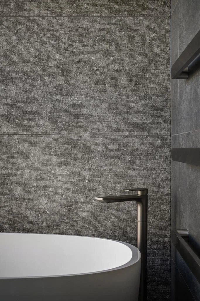 Modern bathroom with freestanding bath and gunmetal tapware detail 
