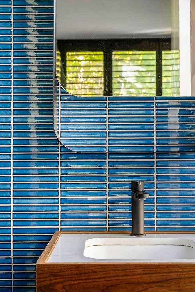Bathroom vanity with blue feature tiles, timber cabinetry and black tapware