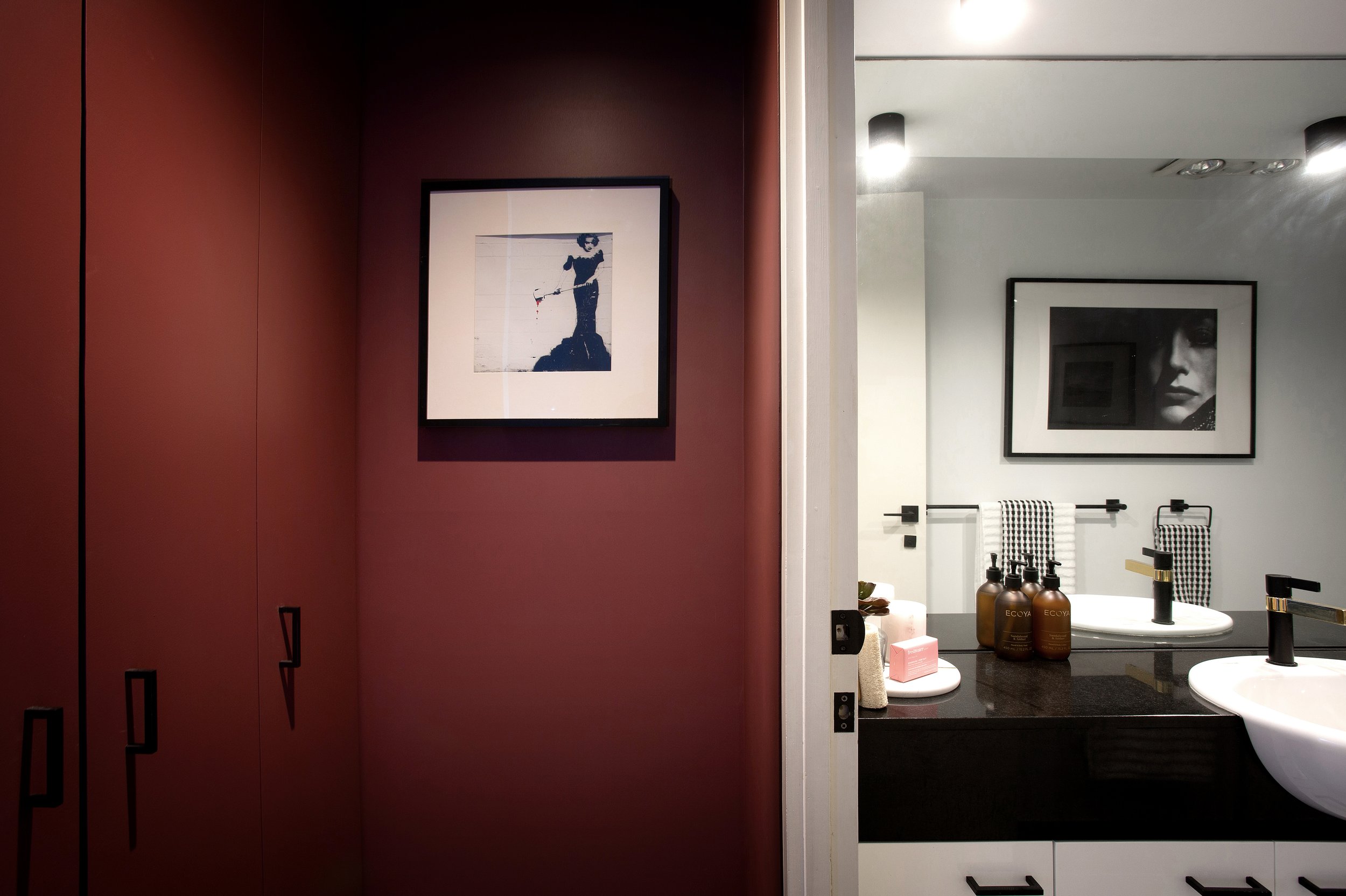 Bedroom to bathroom transition showcasing rich wall colour, framed artwork and modern bathroom styling.