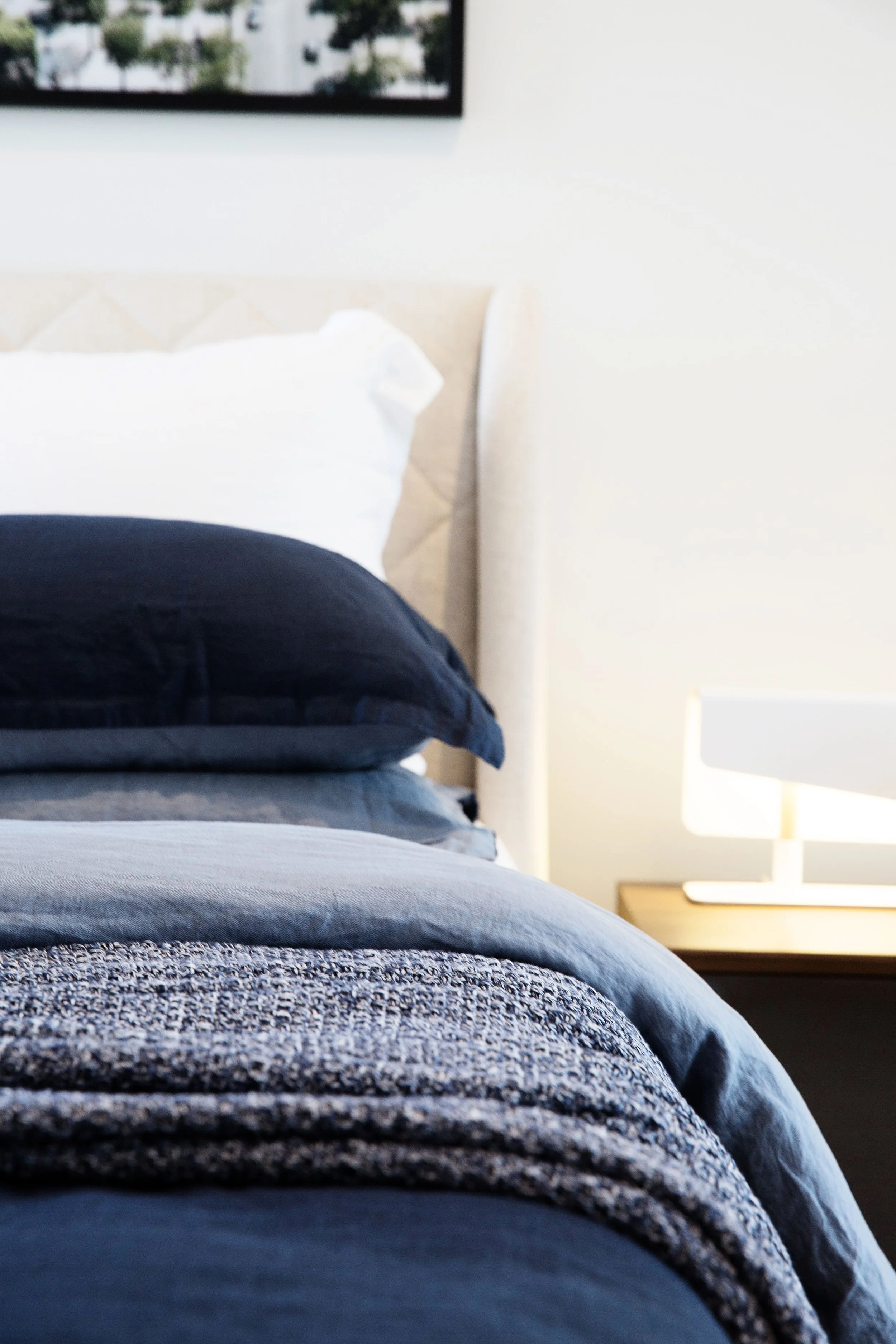 Main bedroom styling in a Docklands townhouse with upholstered bed, layered bedding and soft window furnishings